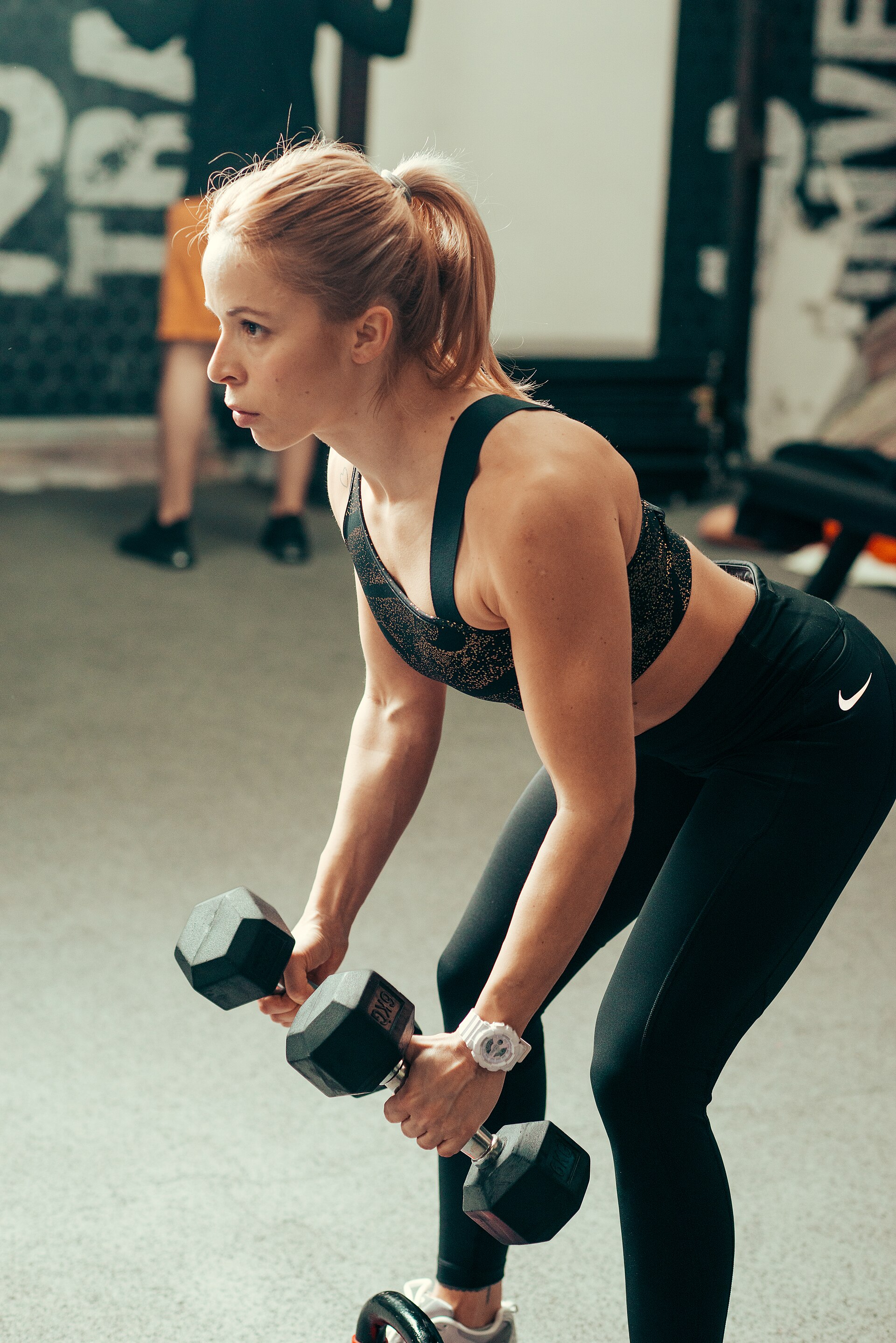 A woman lifting dumbbells in a modern gym