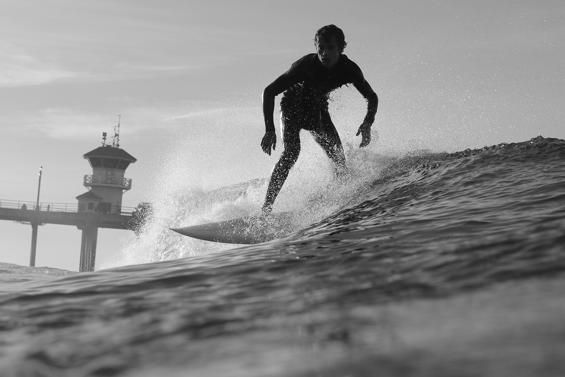 A surfer in a wetsuit walking into the surf