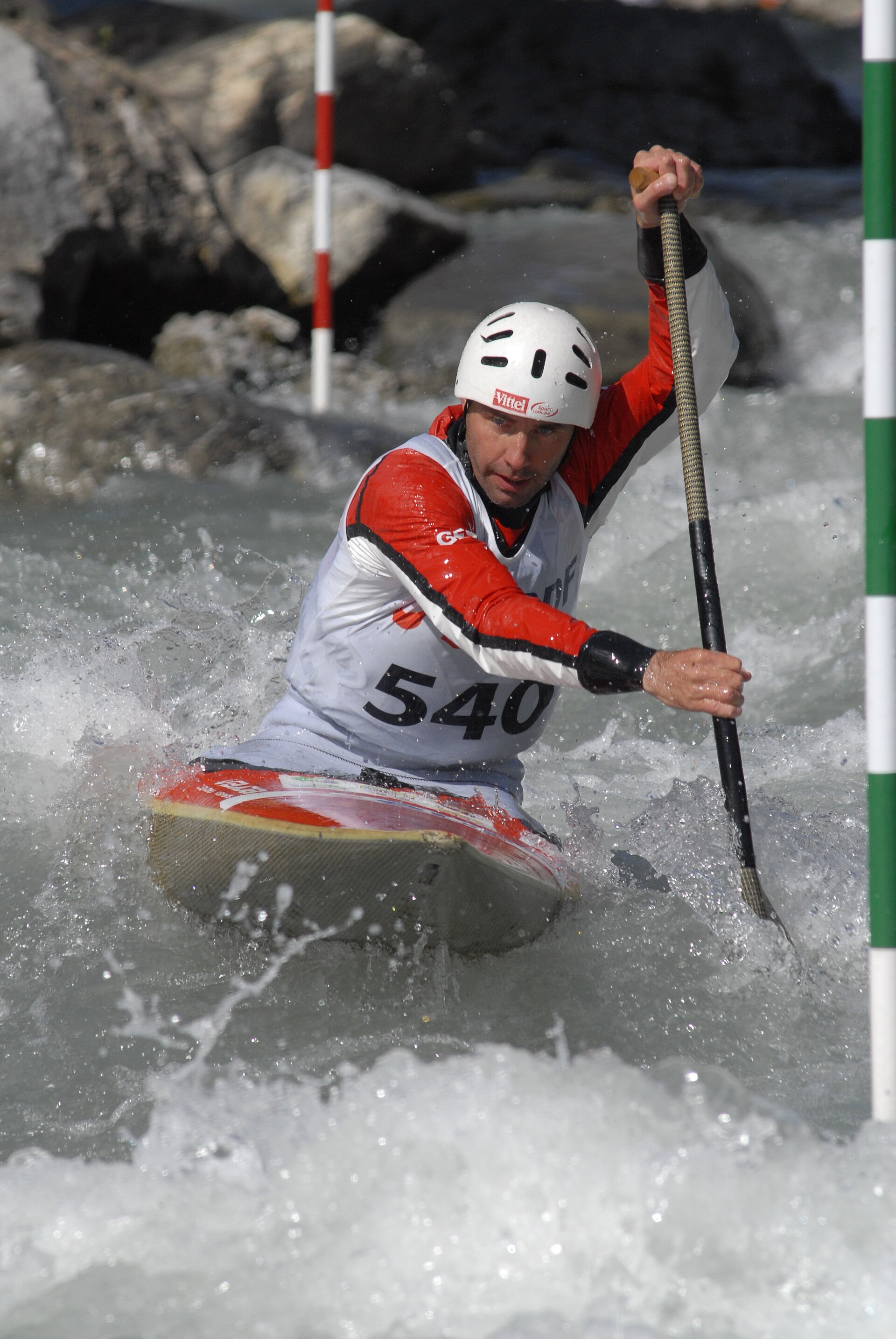 A slalom kayaker threading a gate on whitewater