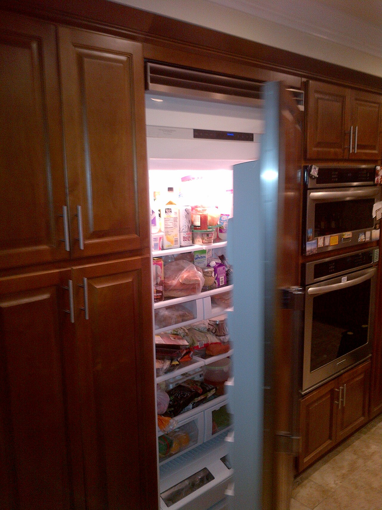 An open refrigerator stocked with food in a home kitchen