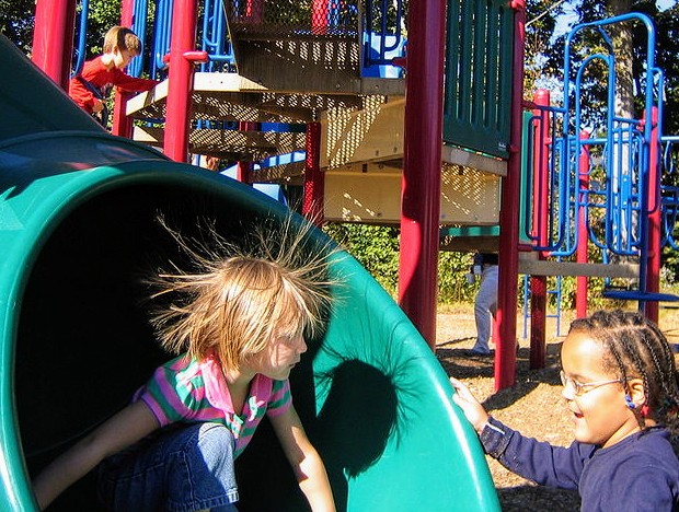 Children on a playground slide showing static-charged hair
