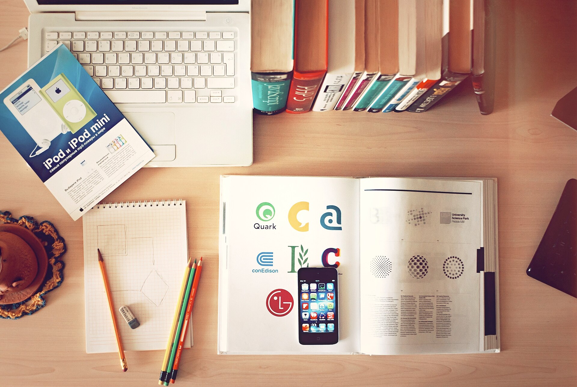 A desk with books, pencils, a laptop, and a phone, the typical setup for a take-home assignment