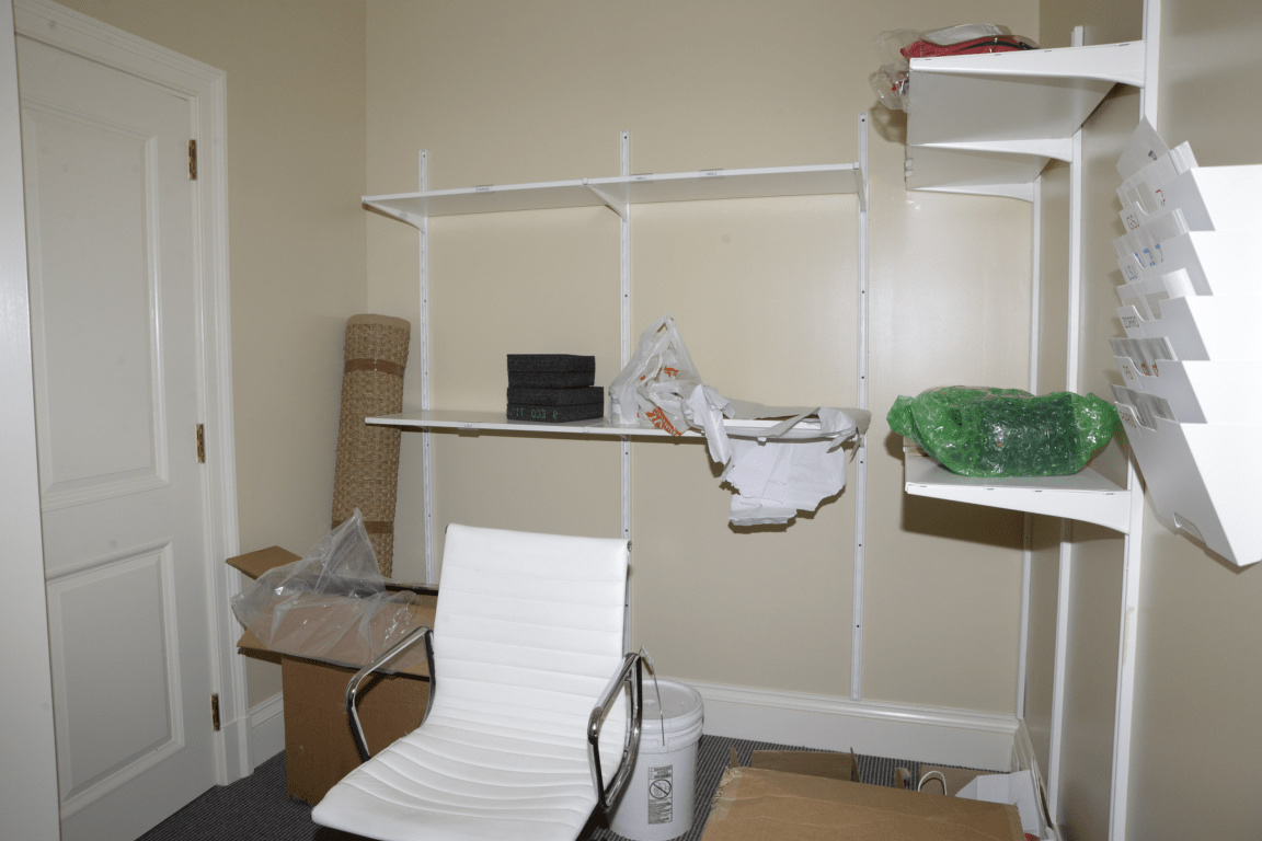 A minimalist office with shelves, a chair, and boxes indicating a move