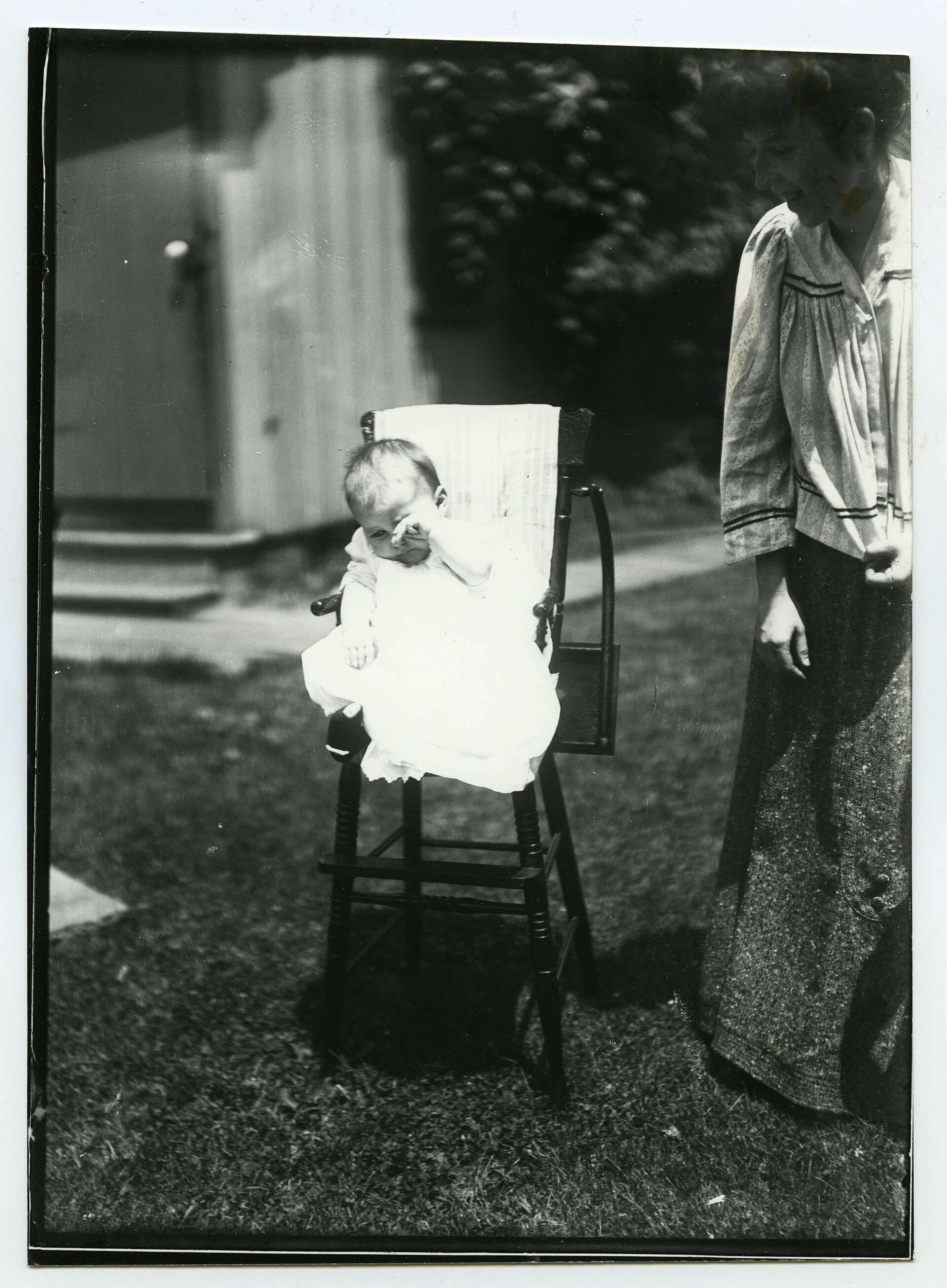 A baby crying in a high chair while a parent looks on