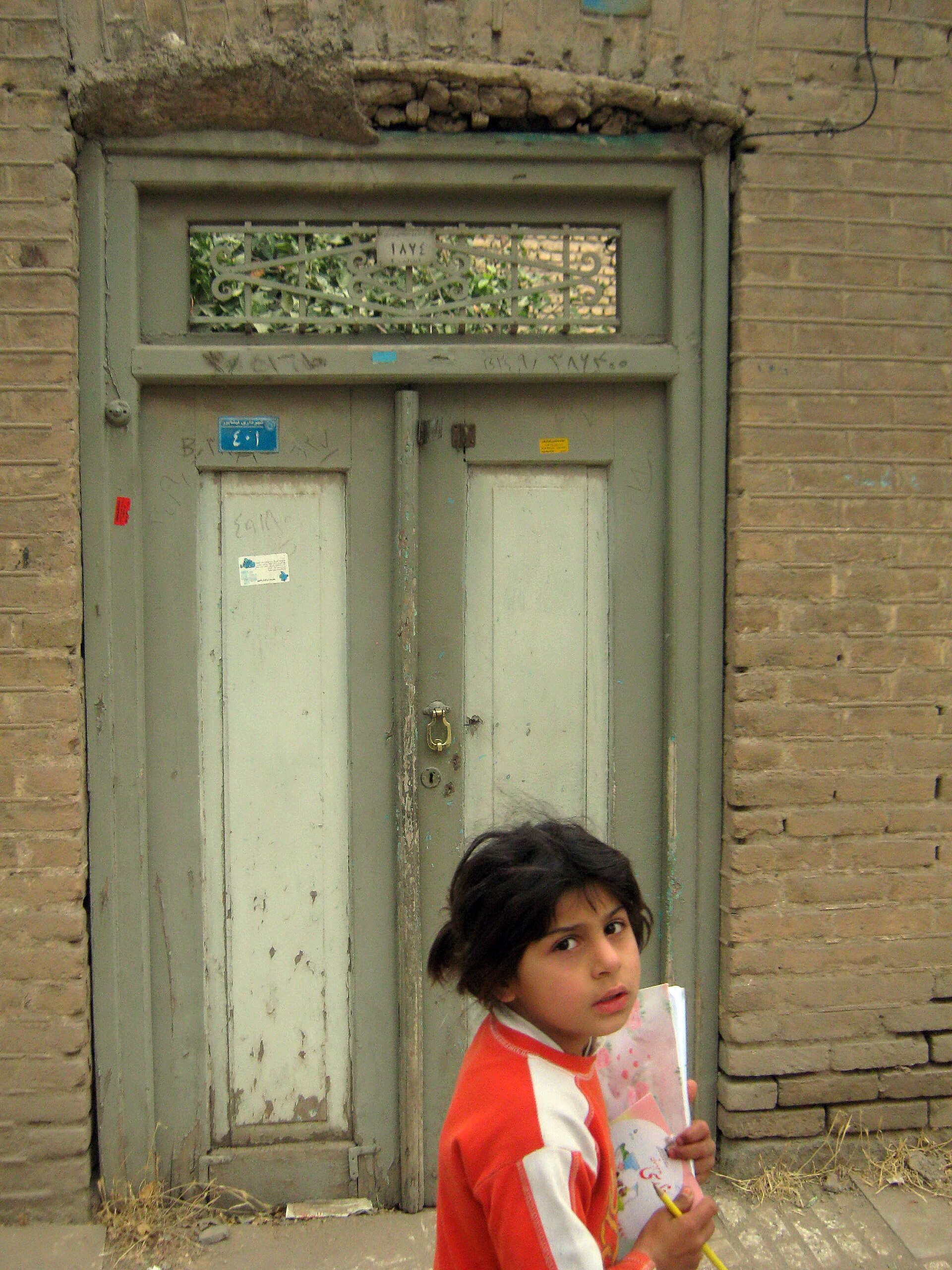 A schoolgirl carrying her textbook past a doorway in Nishapur, Iran