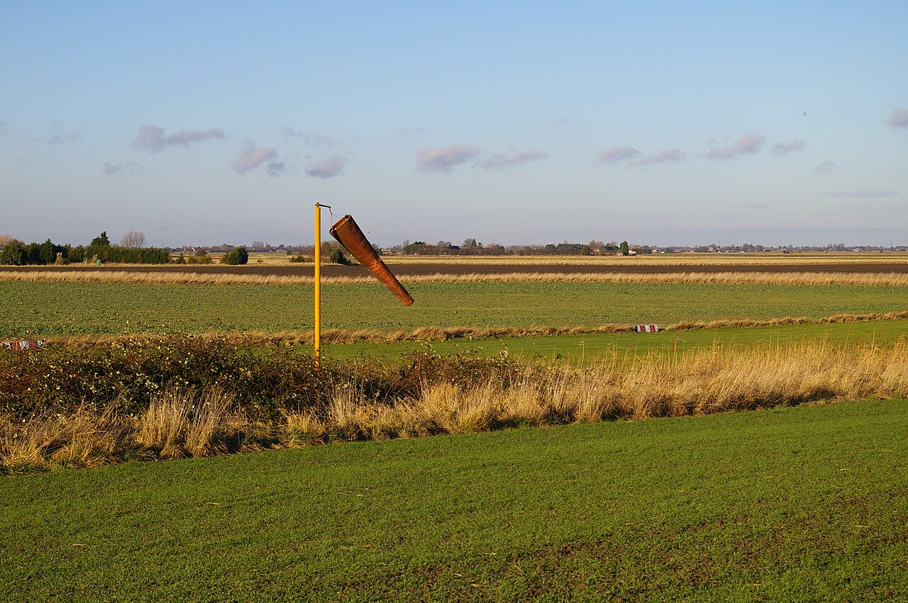 A windsock beside a runway, showing wind direction and strength