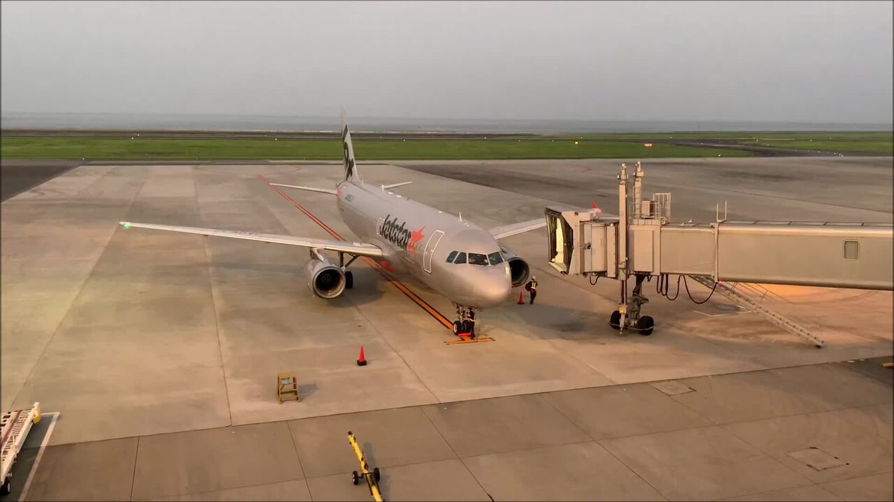 A Jetstar aircraft parked at a jet bridge during boarding