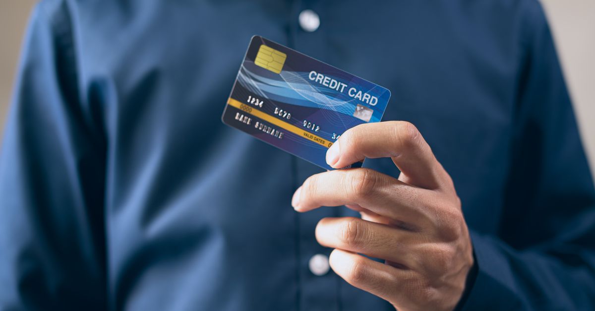A person holding up a blue credit card