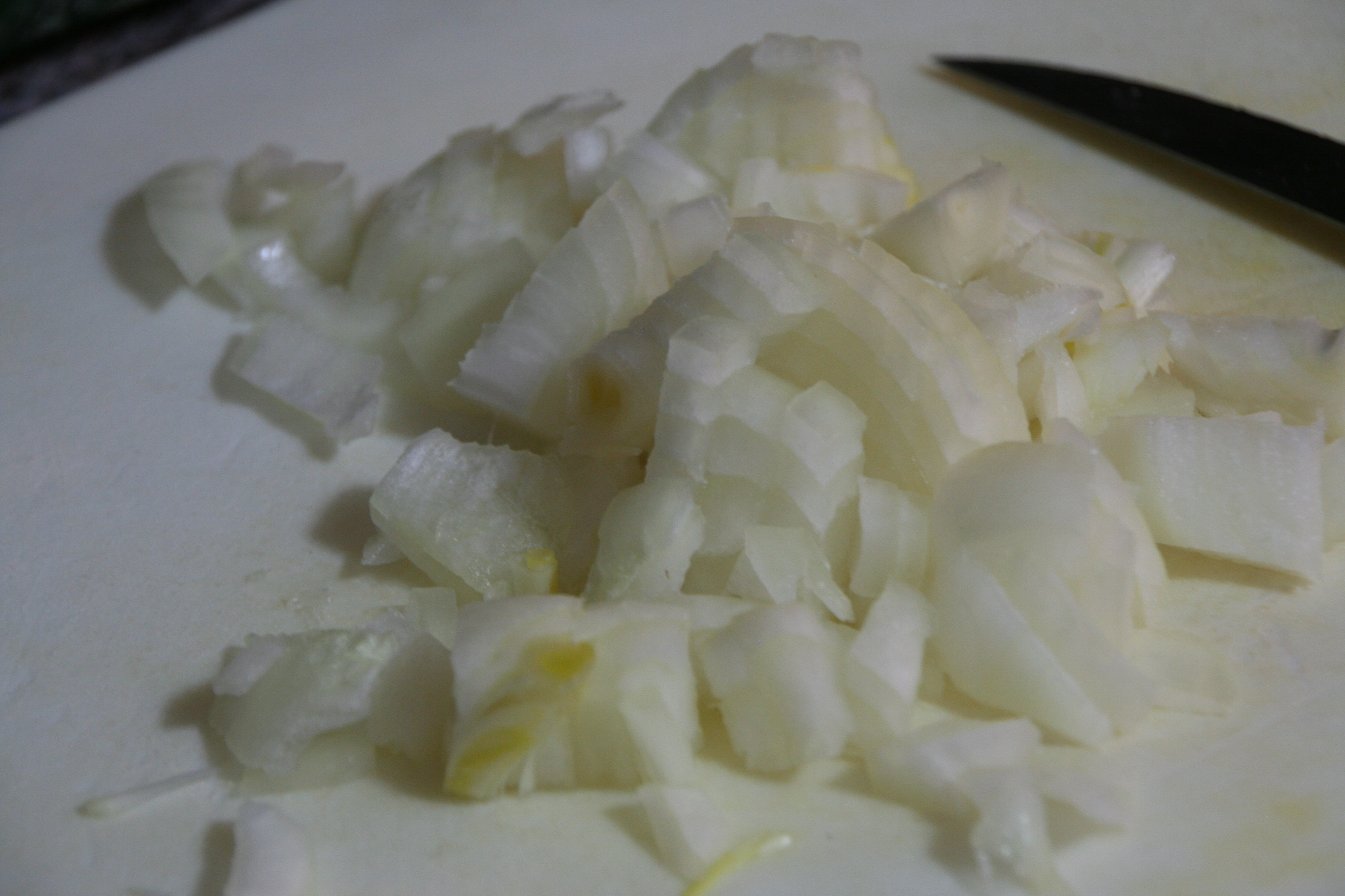 Freshly chopped onions piled on a wooden cutting board