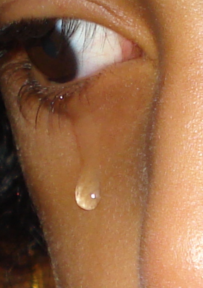A close-up of a tear forming at the corner of an eye