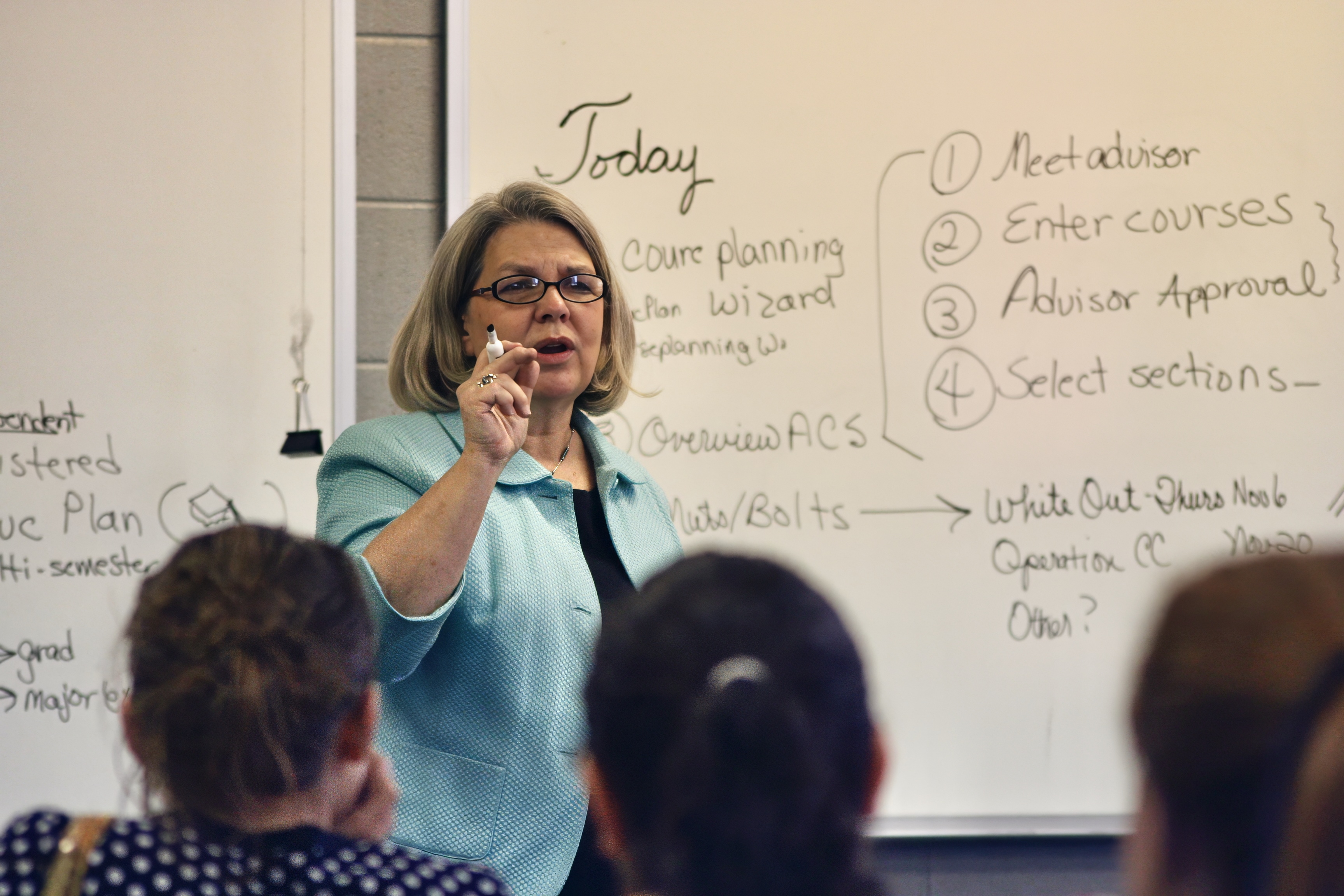 A college professor teaching in a university classroom full of students