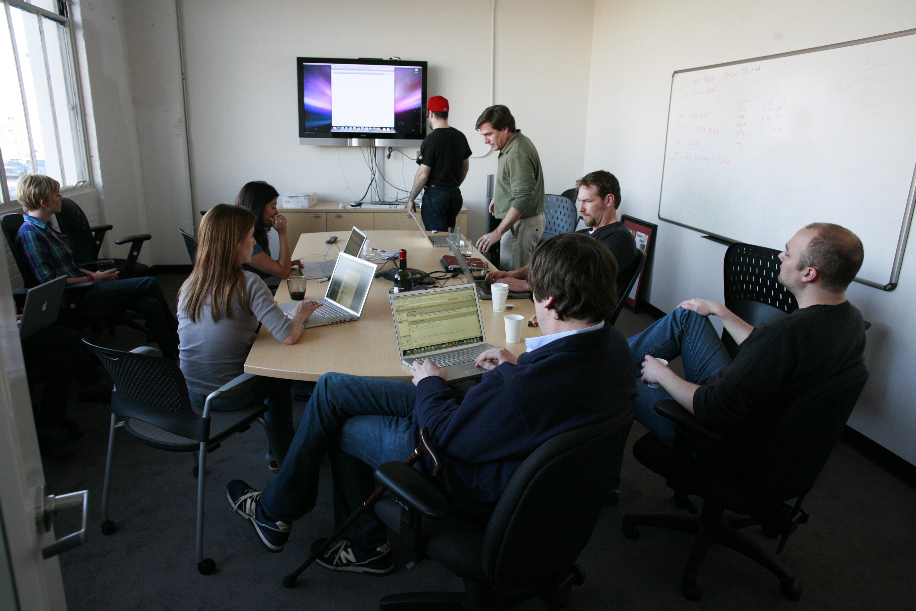 Colleagues working with laptops around a conference room table