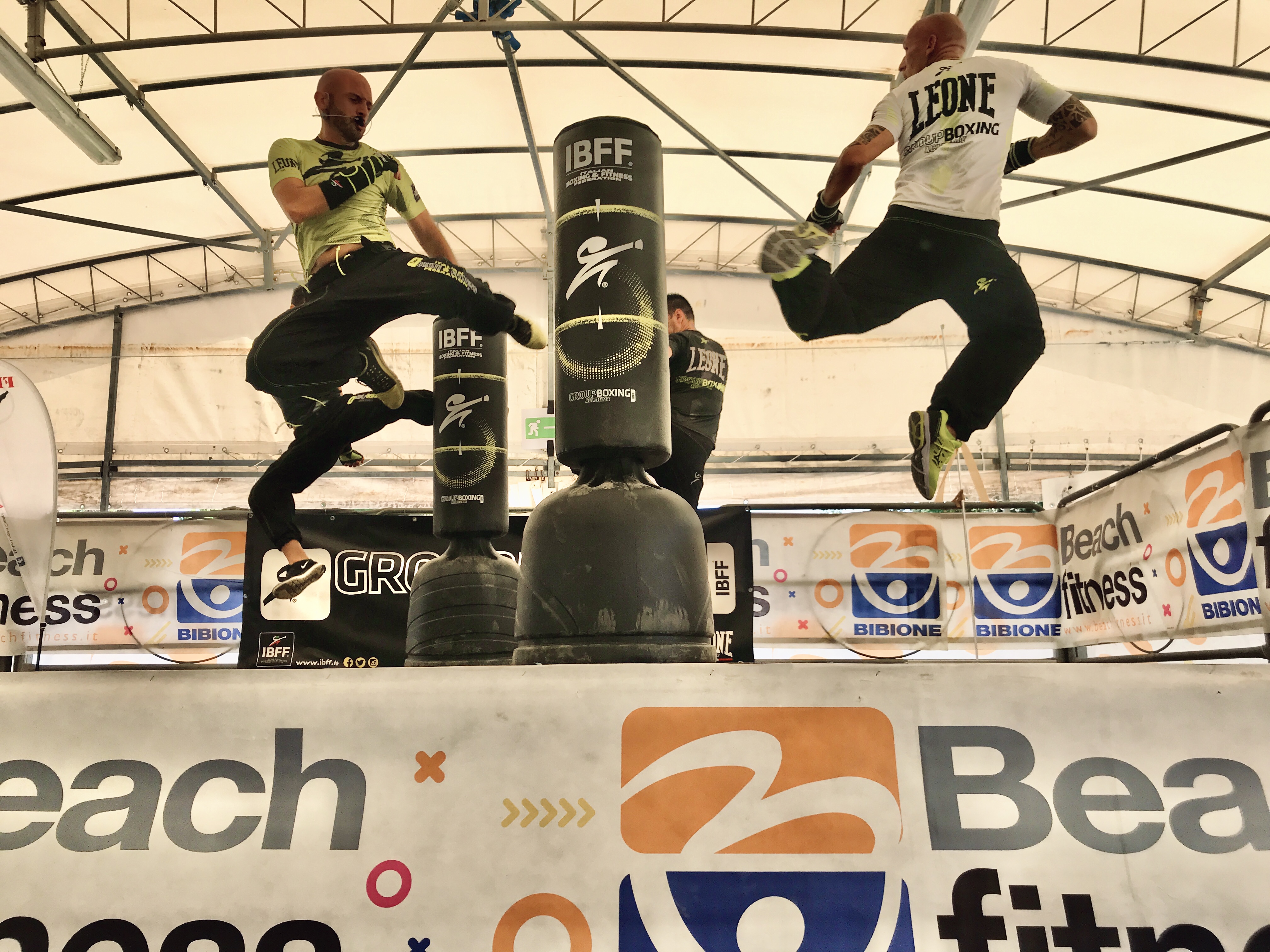 A person mid-jump during a martial arts round kick outdoors
