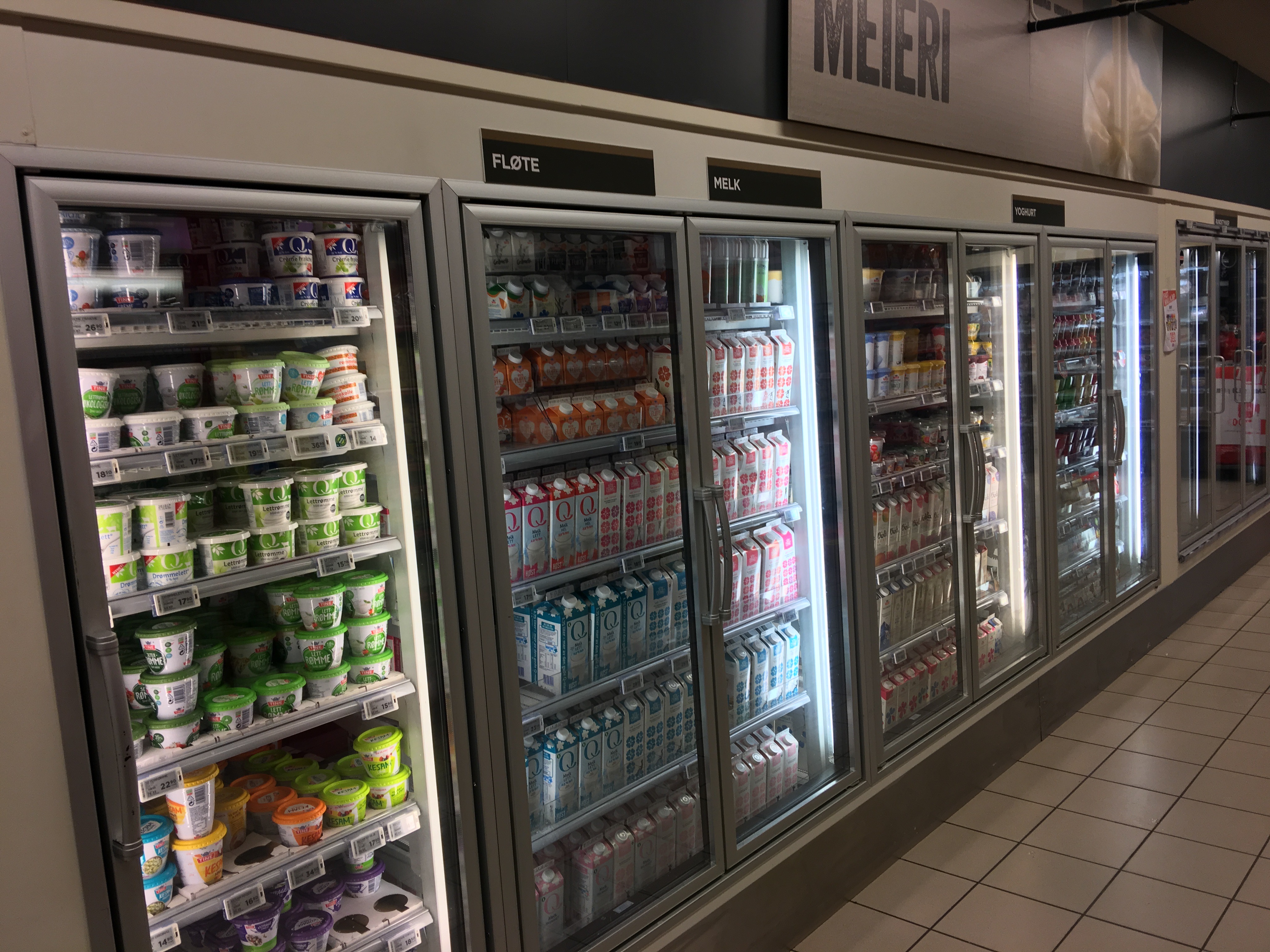 Glass-door fridge shelves stocked with milk and dairy products in a supermarket