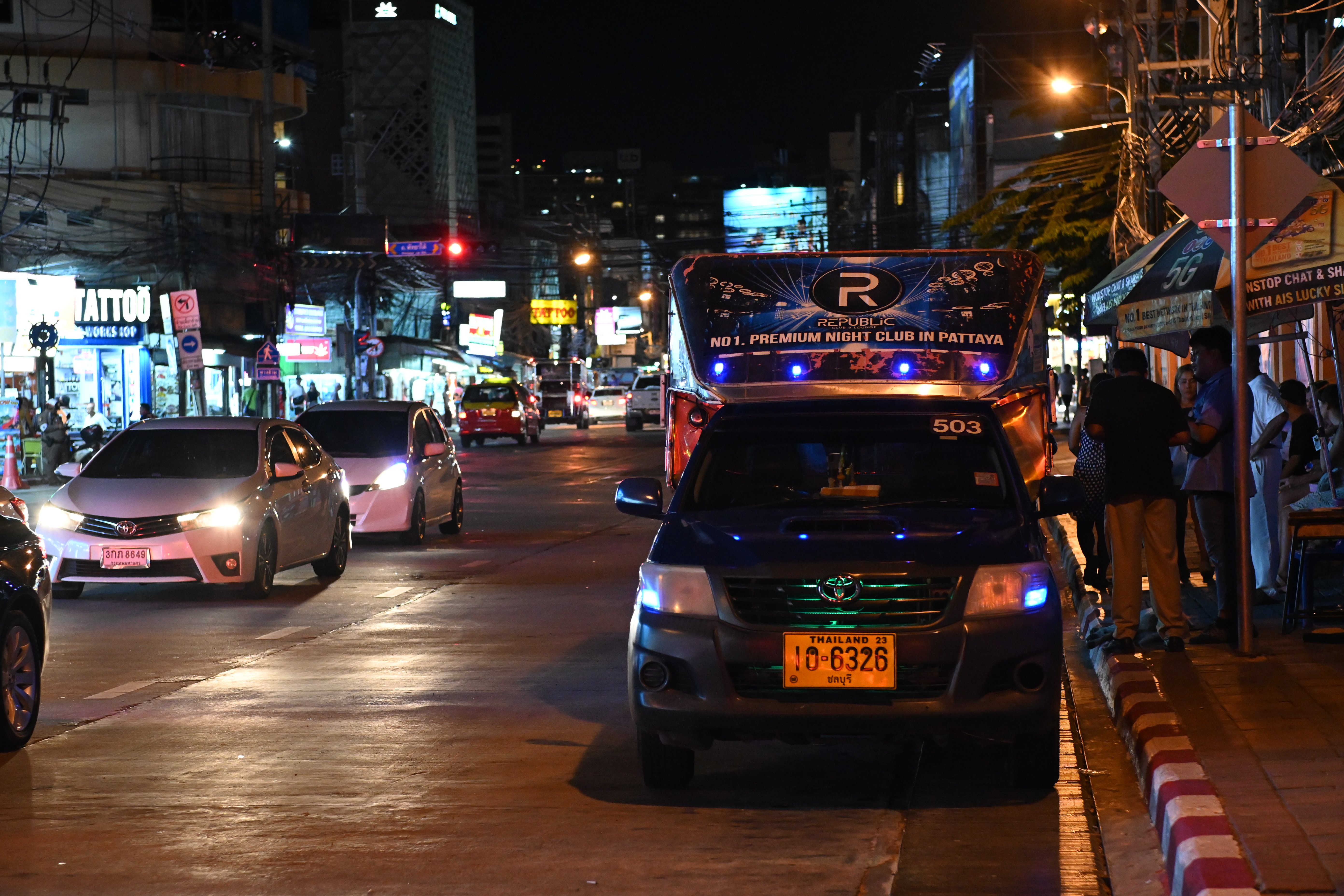 A busy city street at night lit by neon signs