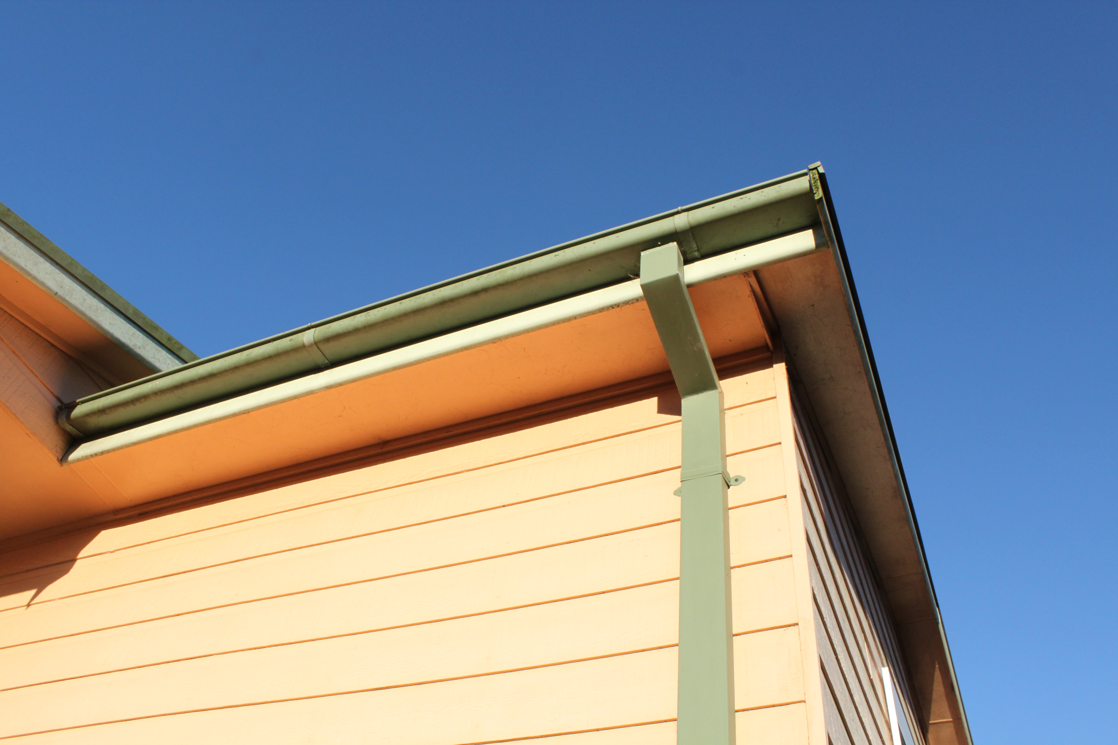 A rain gutter and downspout mounted on the side of a house