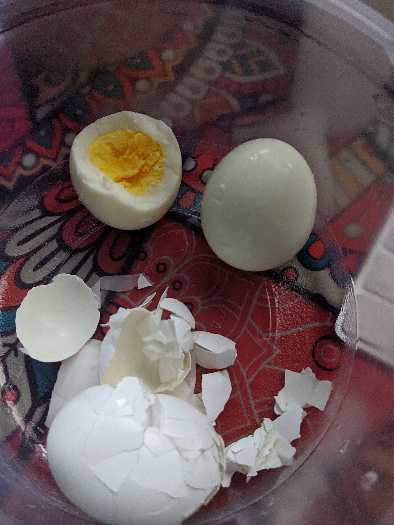 Hard-boiled eggs, one peeled and one halved to show the yolk