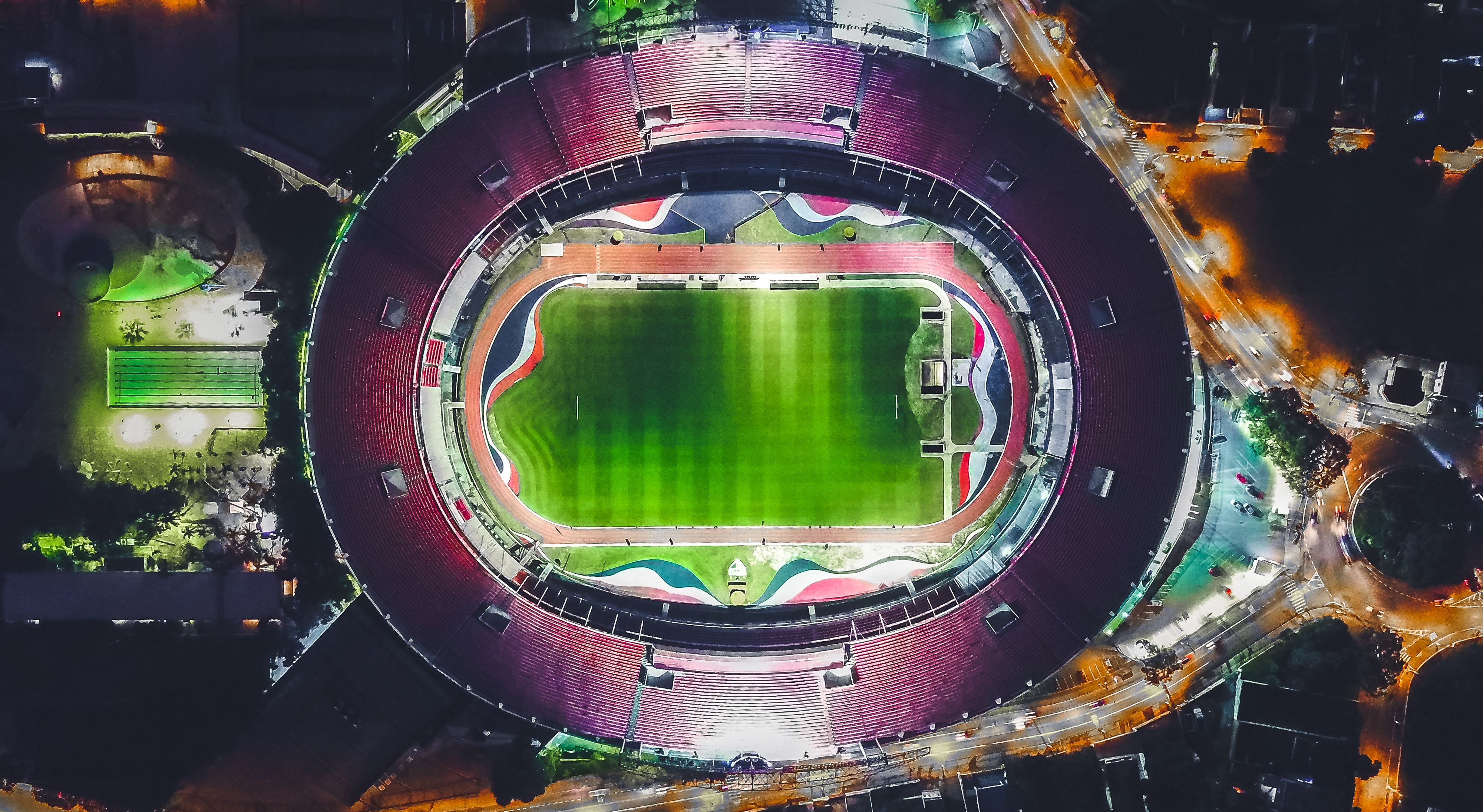 Top-down night view of a large stadium with a lit green field