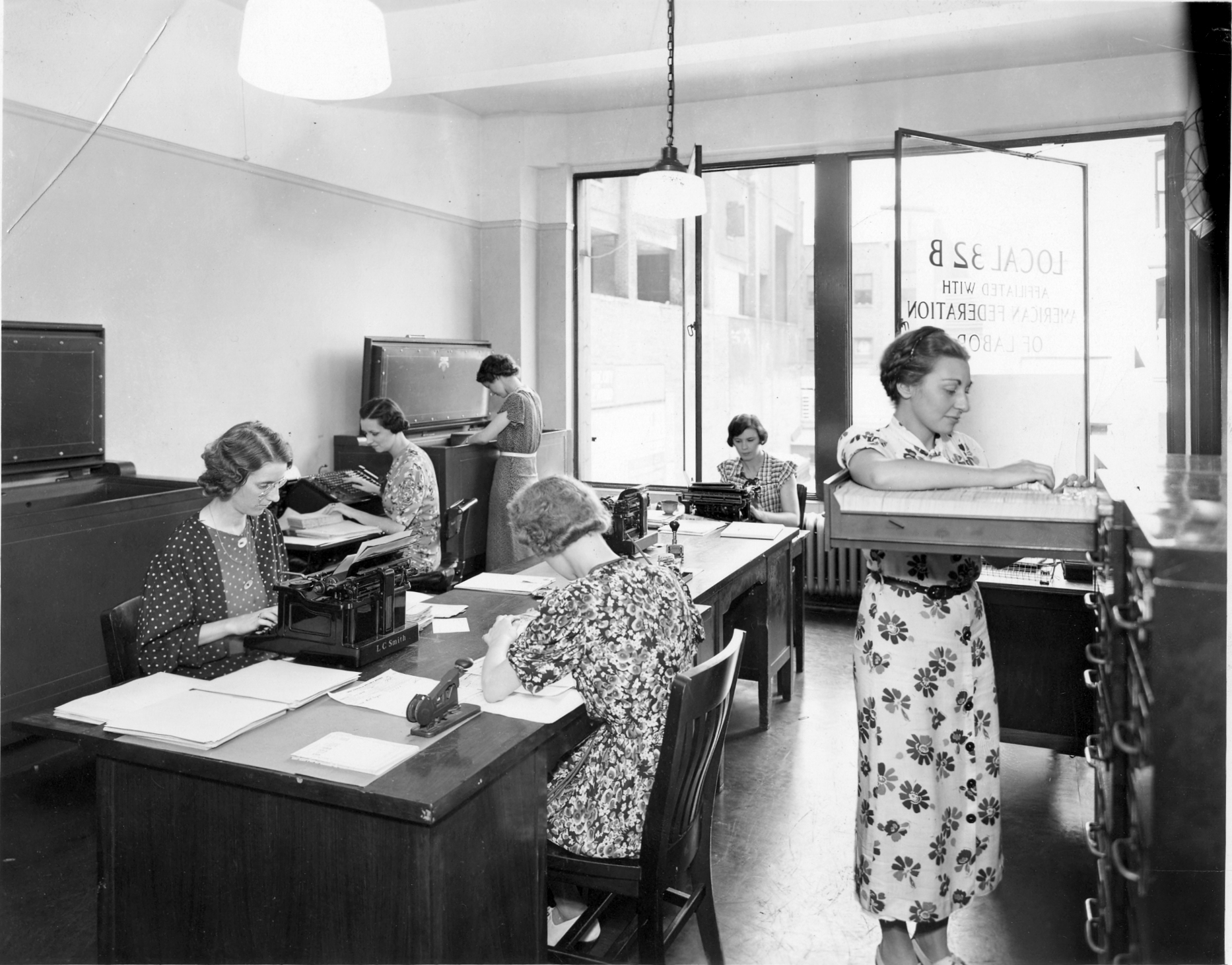 Office workers at their desks in a 1930s office, a reminder that busy workplaces are nothing new