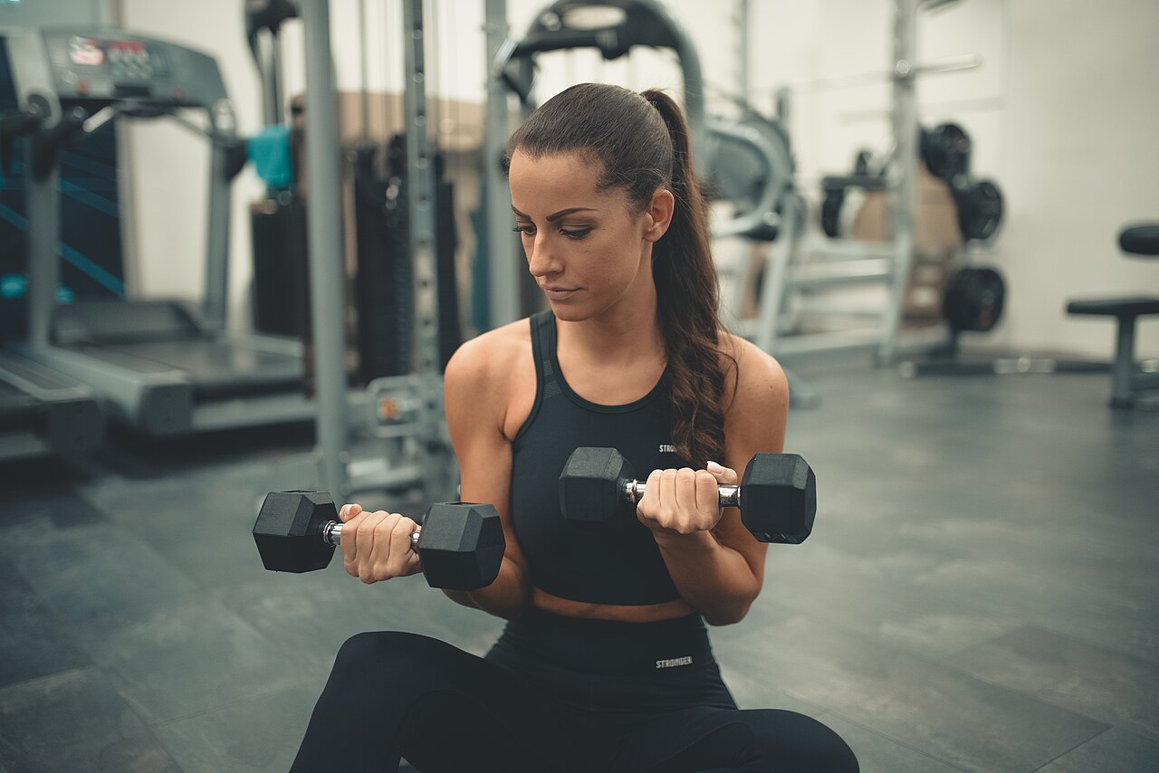 A woman doing dumbbell curls on a gym floor