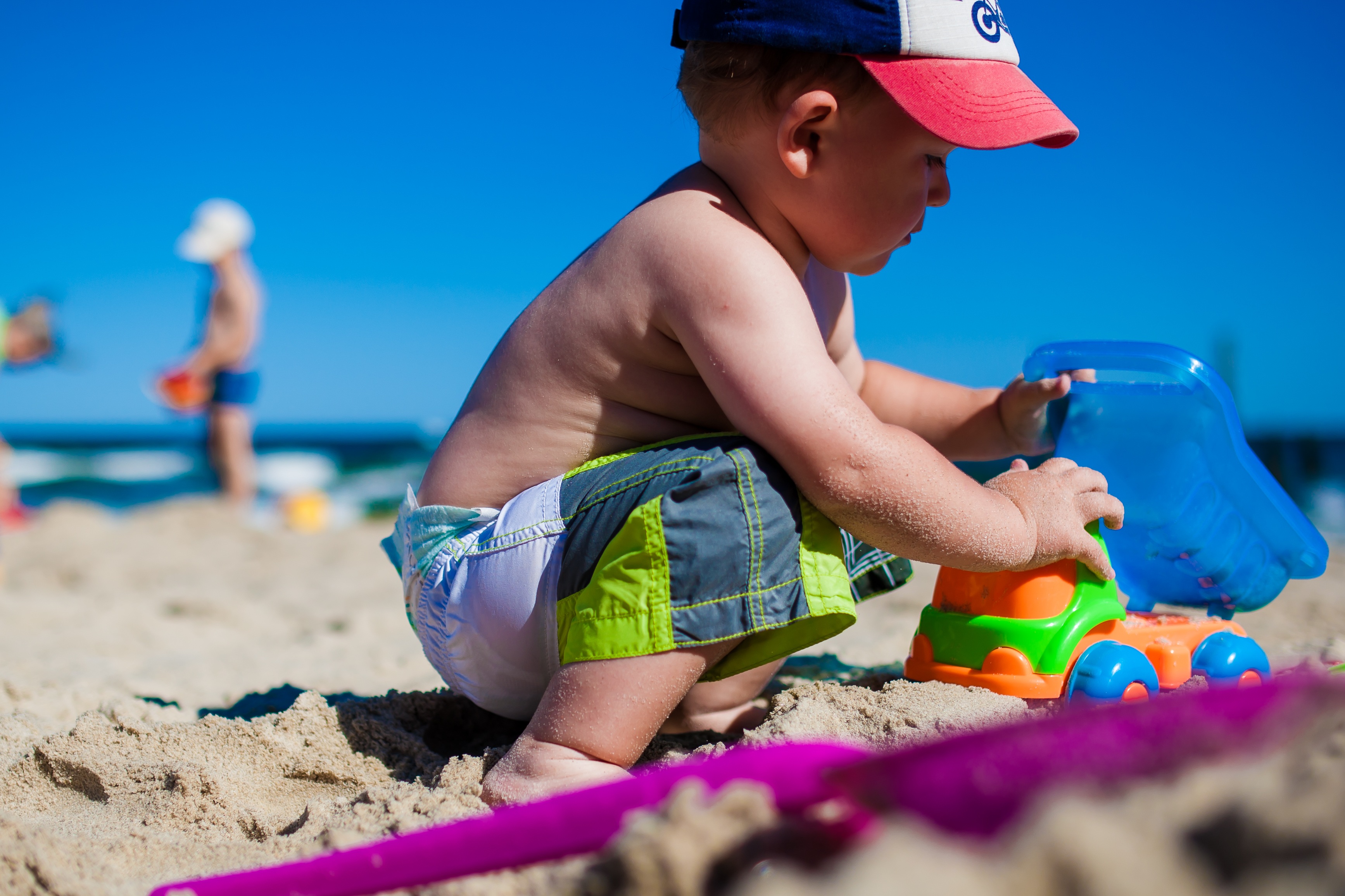 A baby playing with colorful toys on a beach