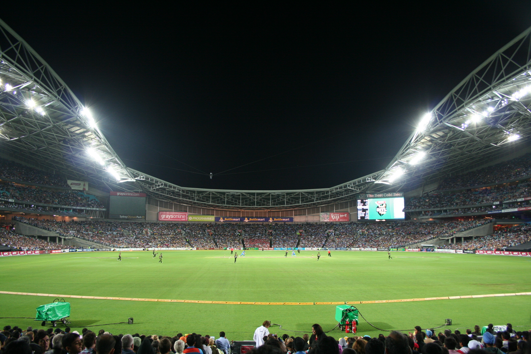 A cricket match in progress with a crowd in the stands