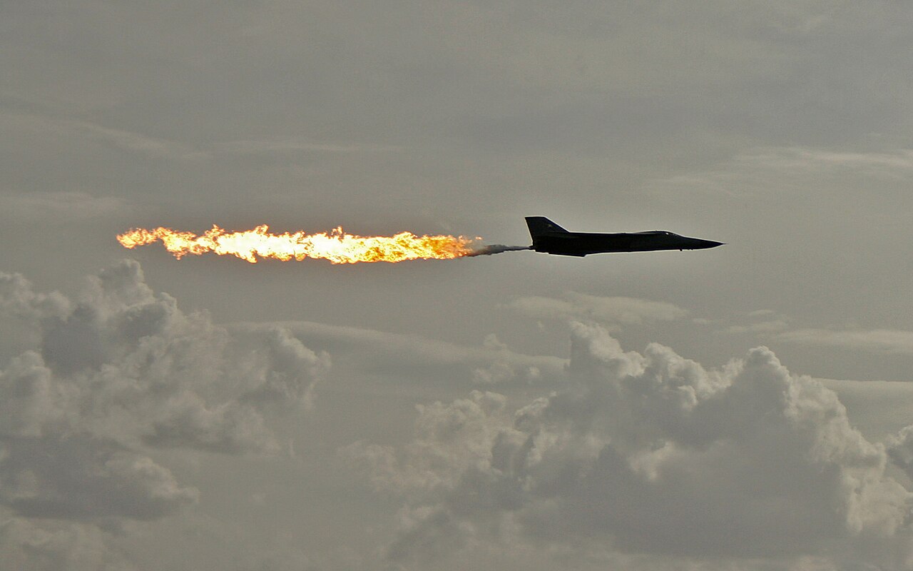 An F-111 aircraft trailing twin streams of dumped fuel at an airshow