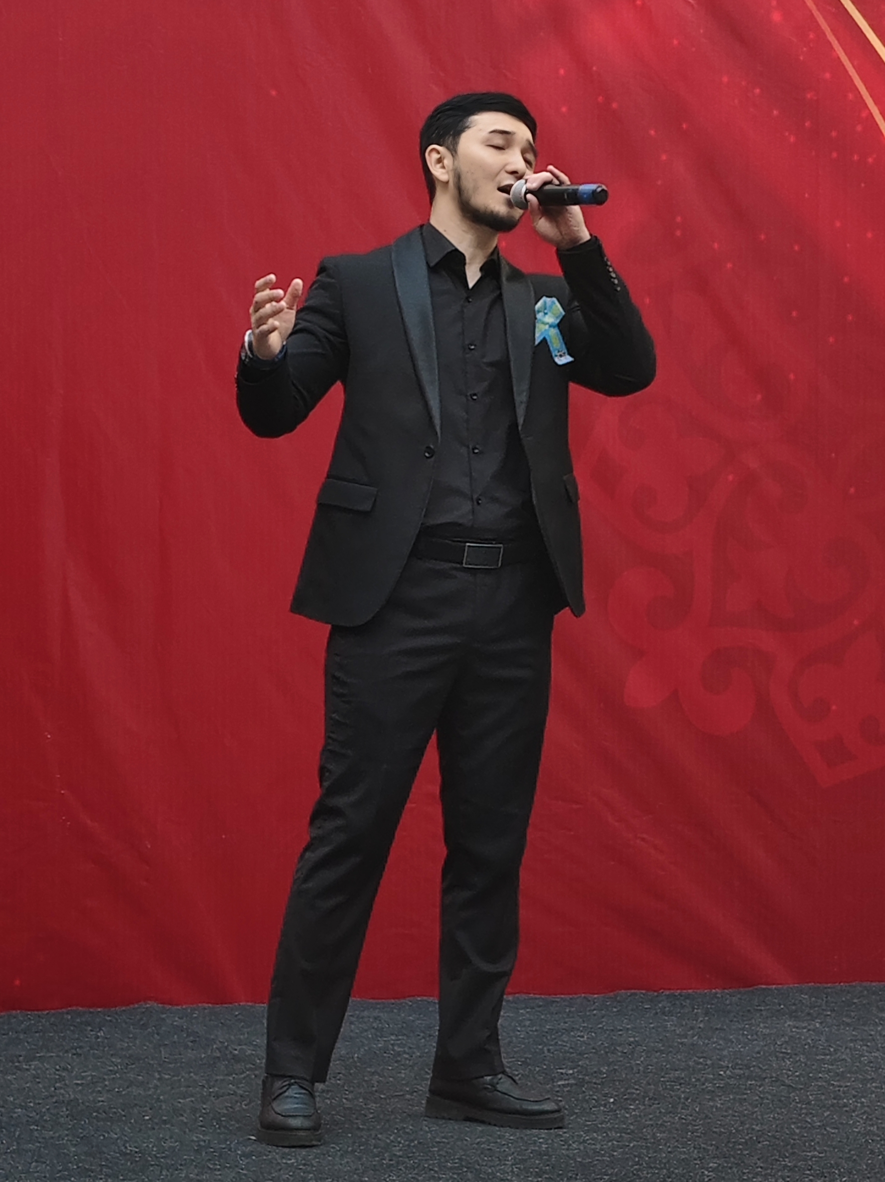 A male vocalist singing into a microphone on a concert stage