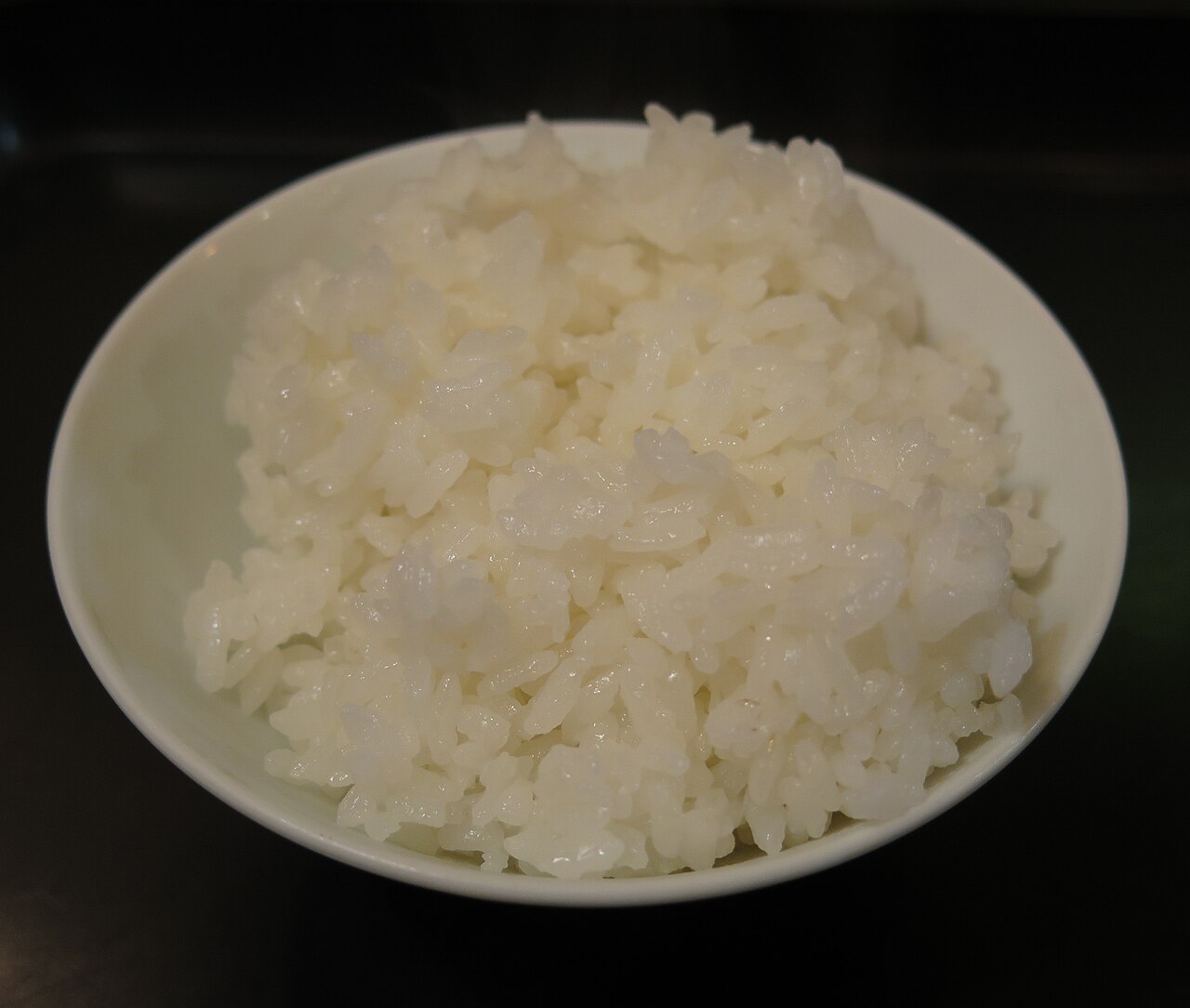 Steaming bowl of cooked white rice photographed from above