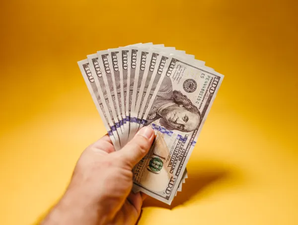A hand fanning out one-hundred-dollar bills