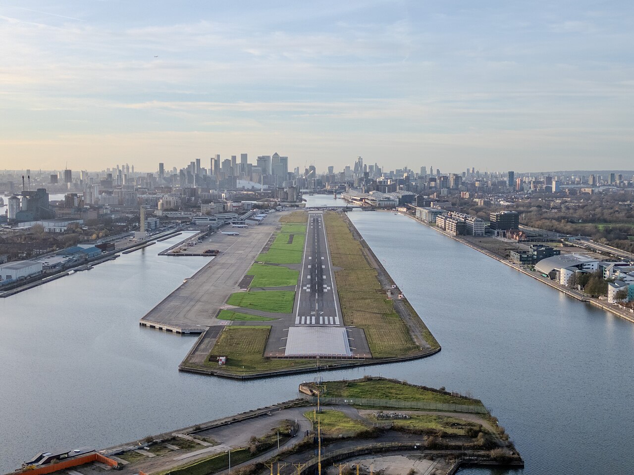 Aerial view of London City Airport with its single runway stretching between the docks