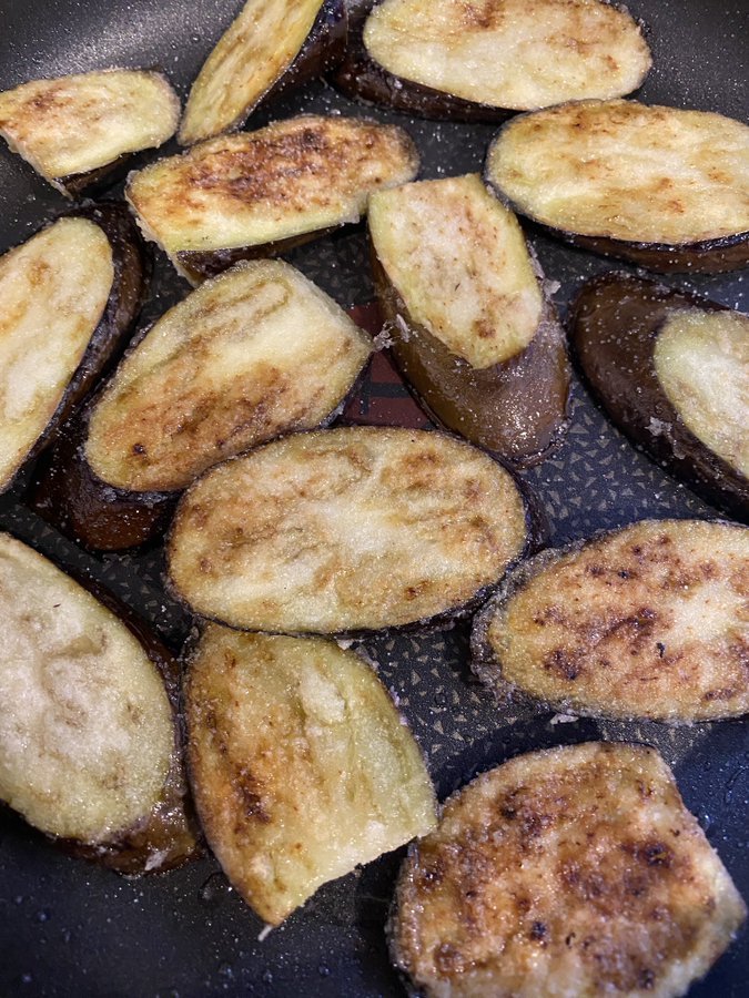 Eggplant slices roasting in a frying pan