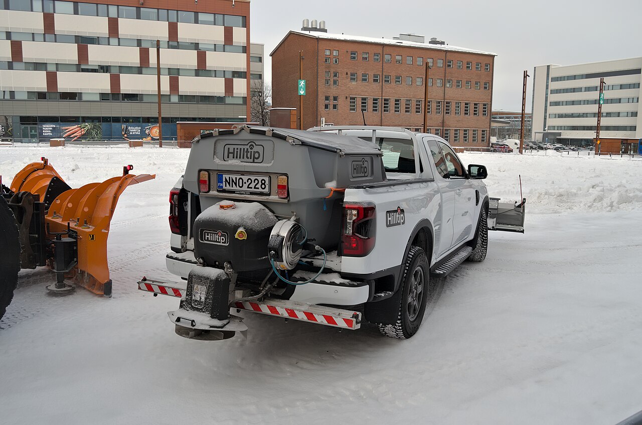 A pickup truck with a salt spreader at a winter road event