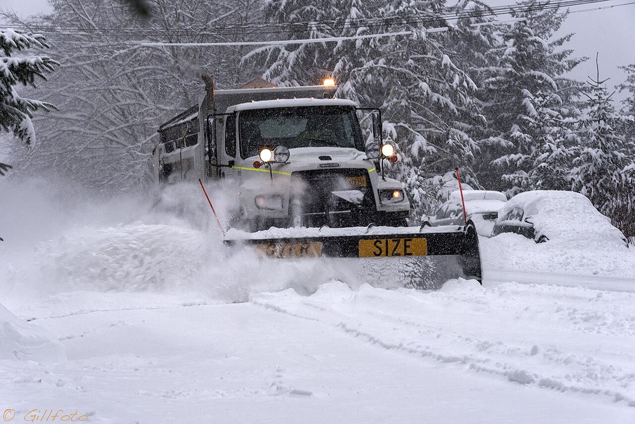 A municipal plow truck spreading deicer on a winter road