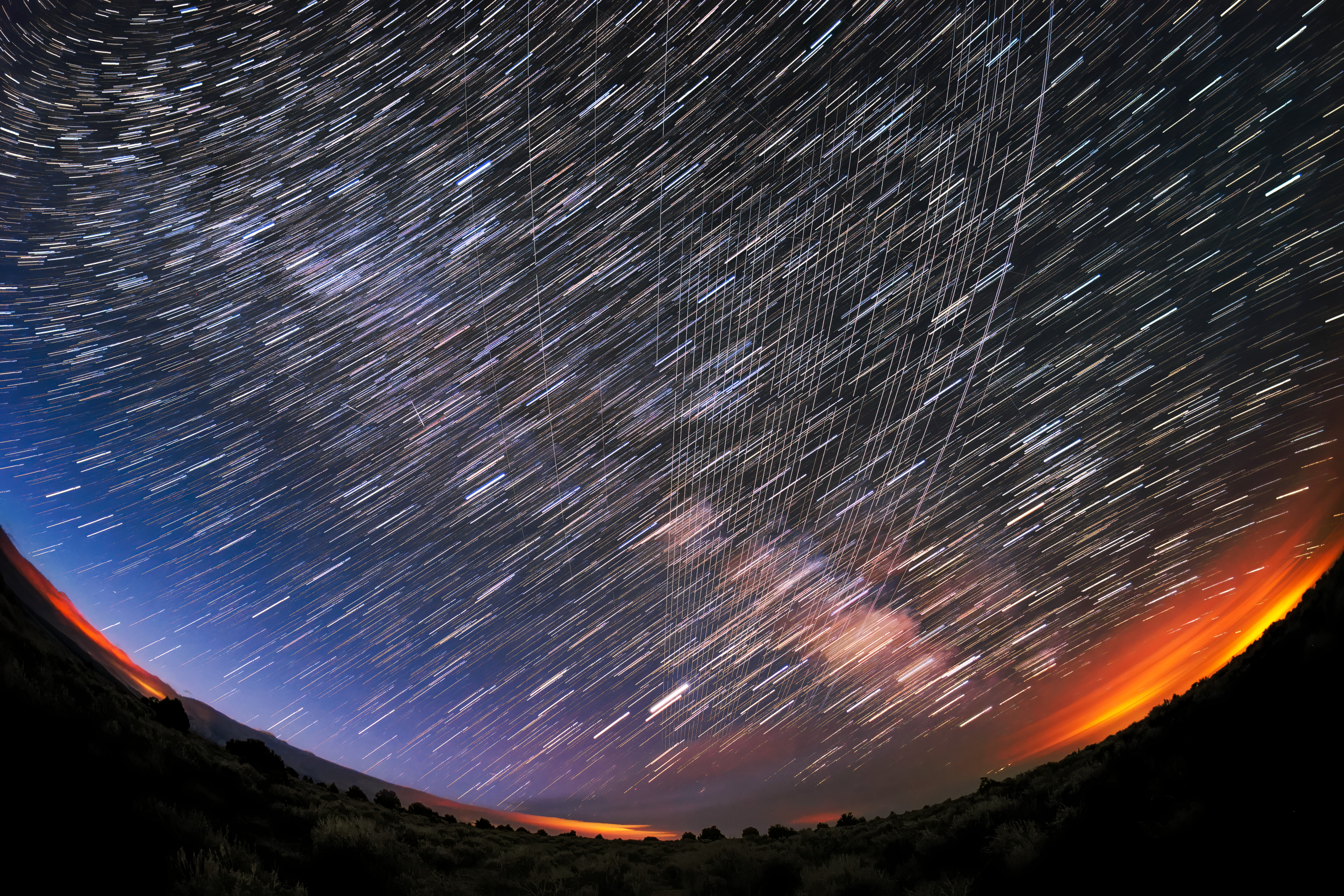 Starlink satellites passing overhead in the night sky above a national forest, photographed soon after launch