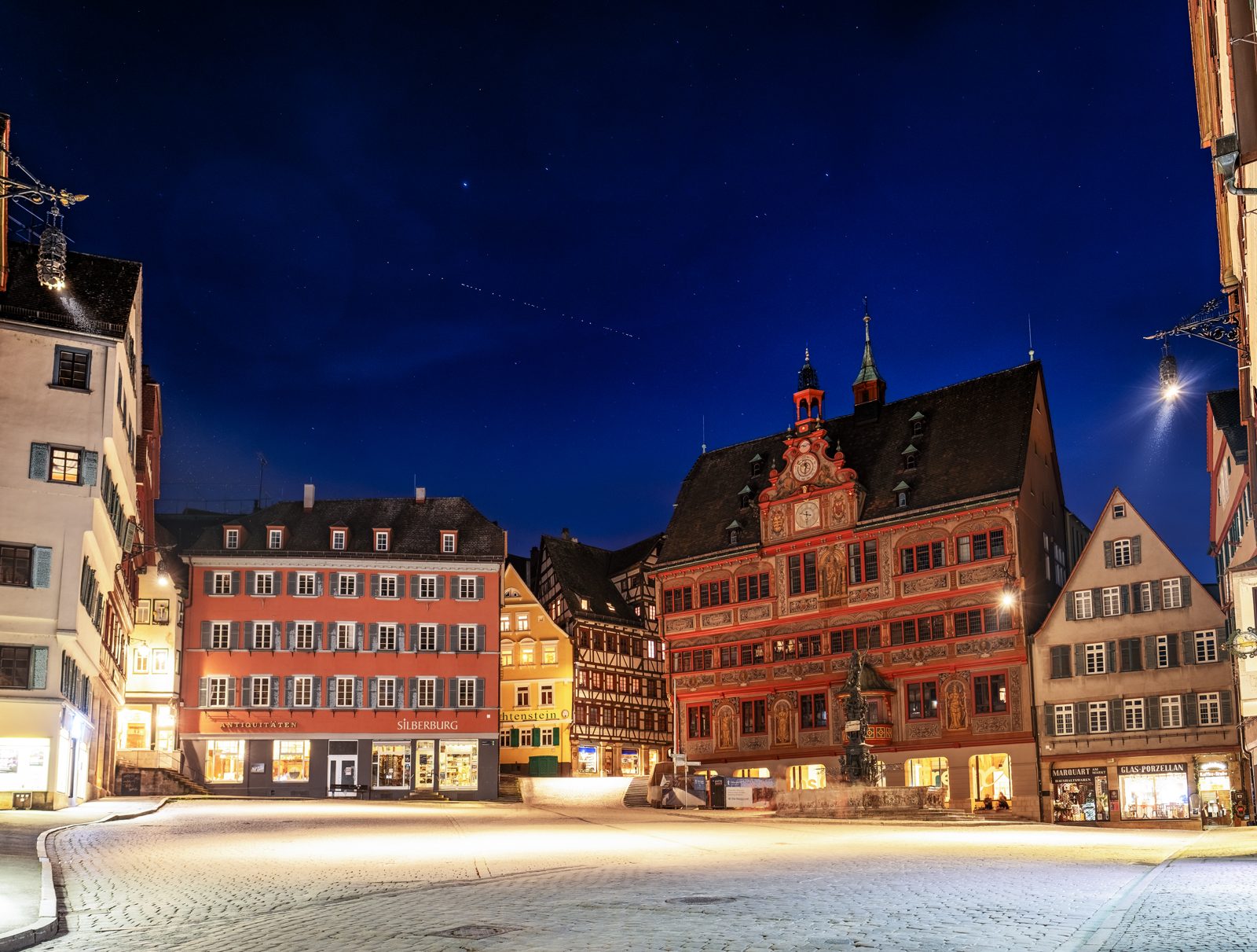 A train of Starlink satellites crossing the night sky over a town, the visible sign of the constellation growth behind phone satellite features