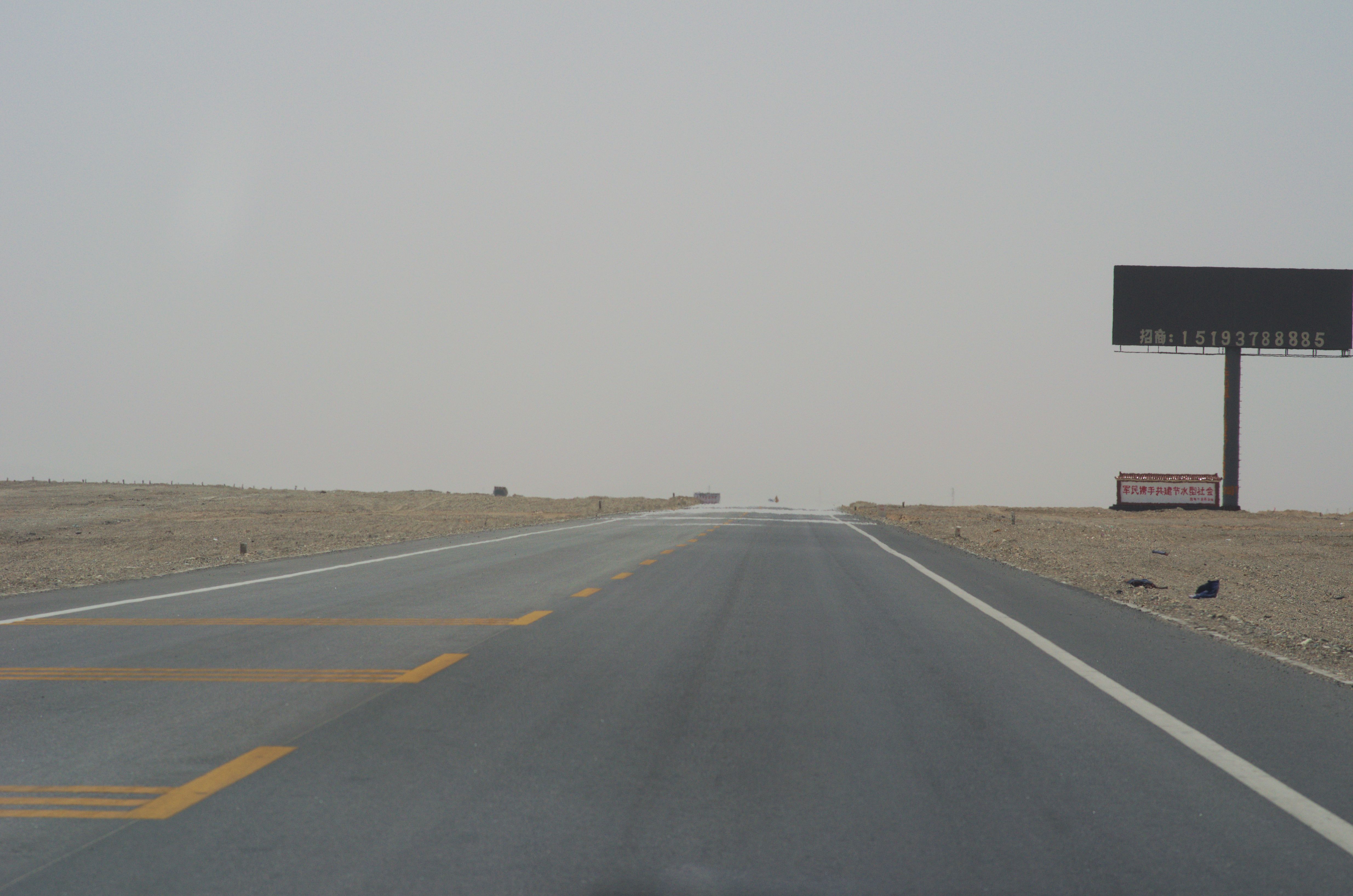 A mirage shimmering above a hot desert road, appearing as a patch of water in the distance