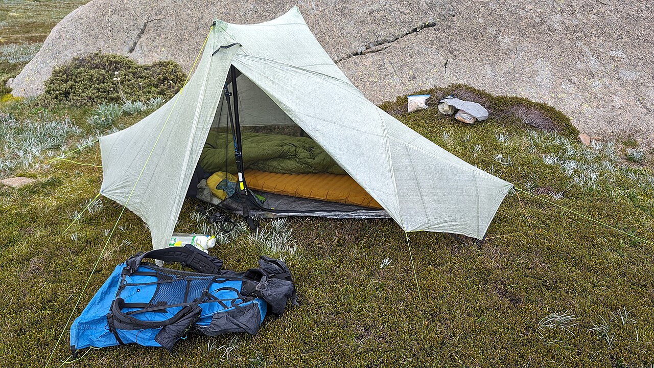 A tent with a sleeping bag and backpack set up at a campsite