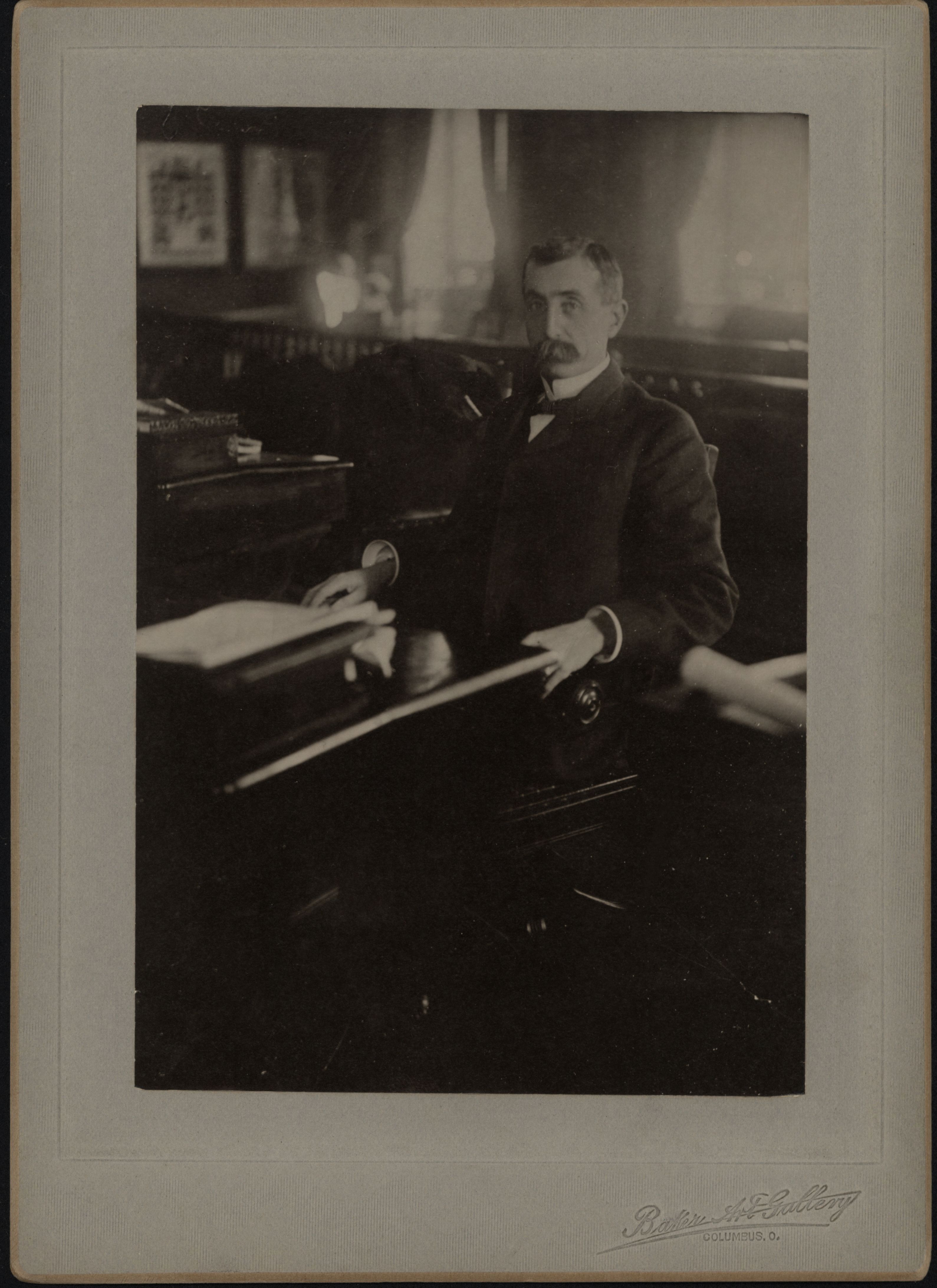 A 19th-century studio portrait of a suited man seated at a desk