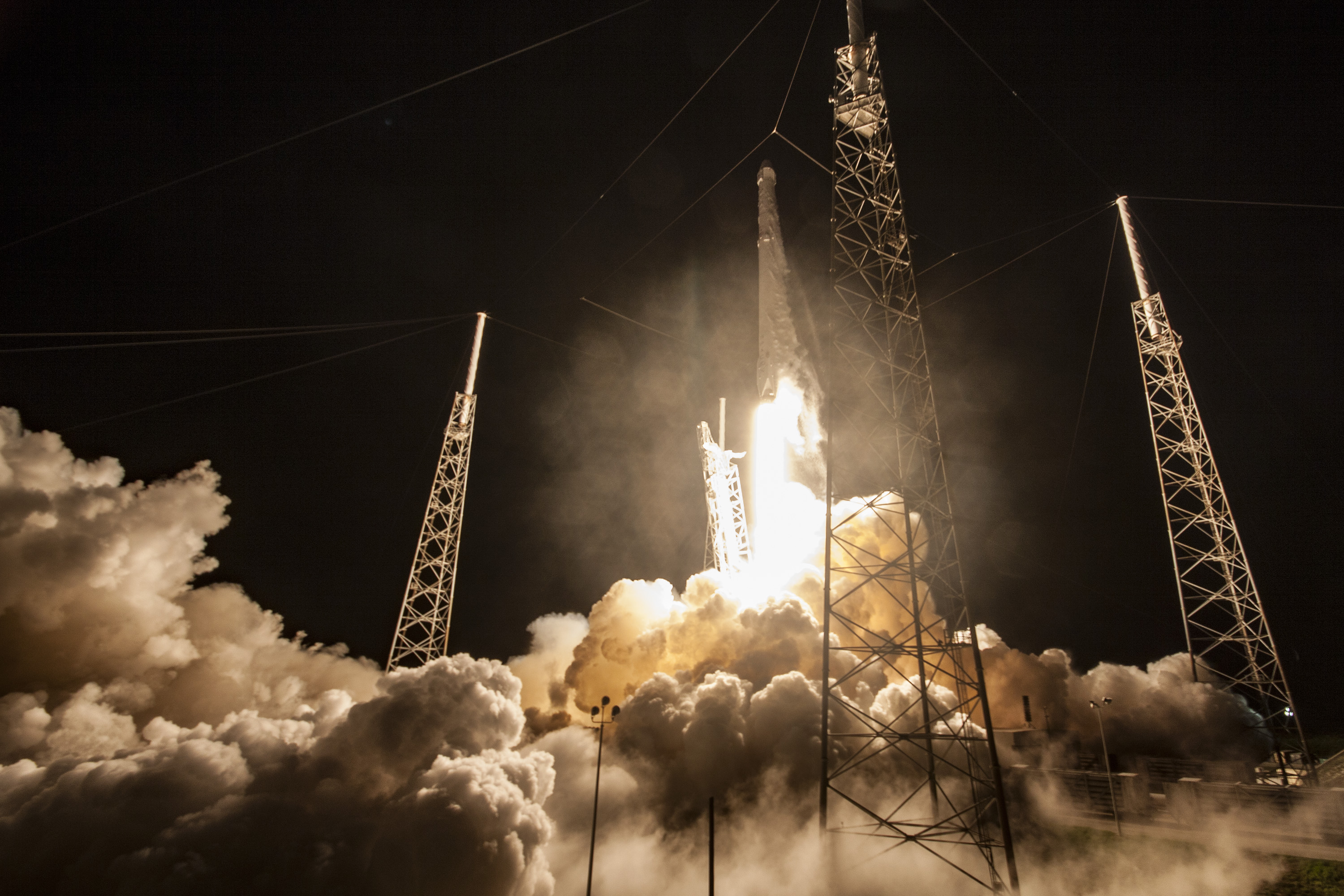 A Falcon 9 rocket lifts off at night, leaving a bright trail in the dark sky
