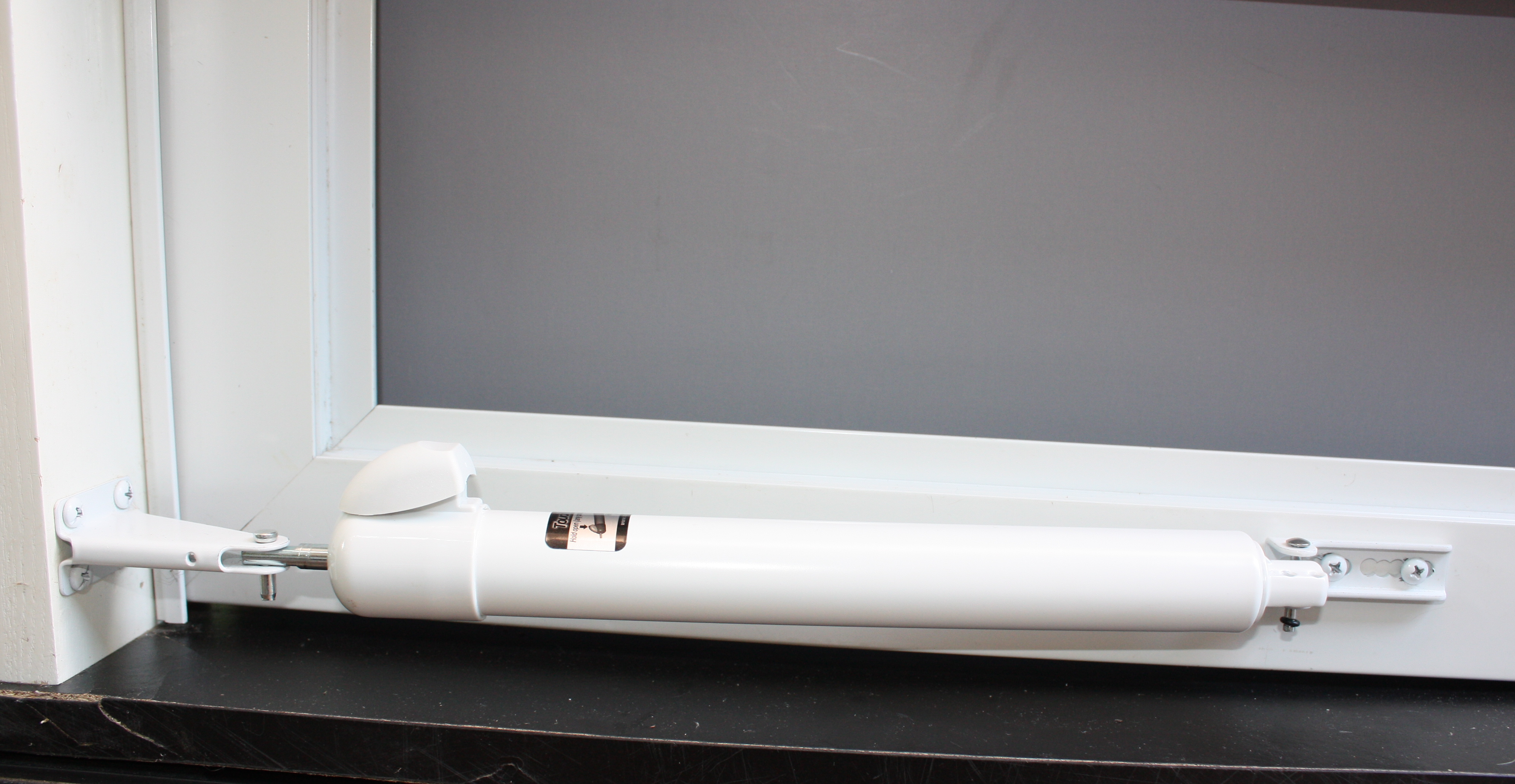 A pneumatic door closer mounted at the top of an interior door