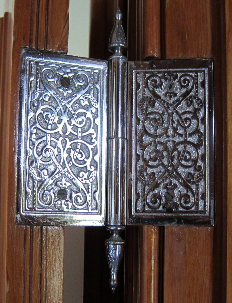 An ornate interior door hinge with decorative mounting plates