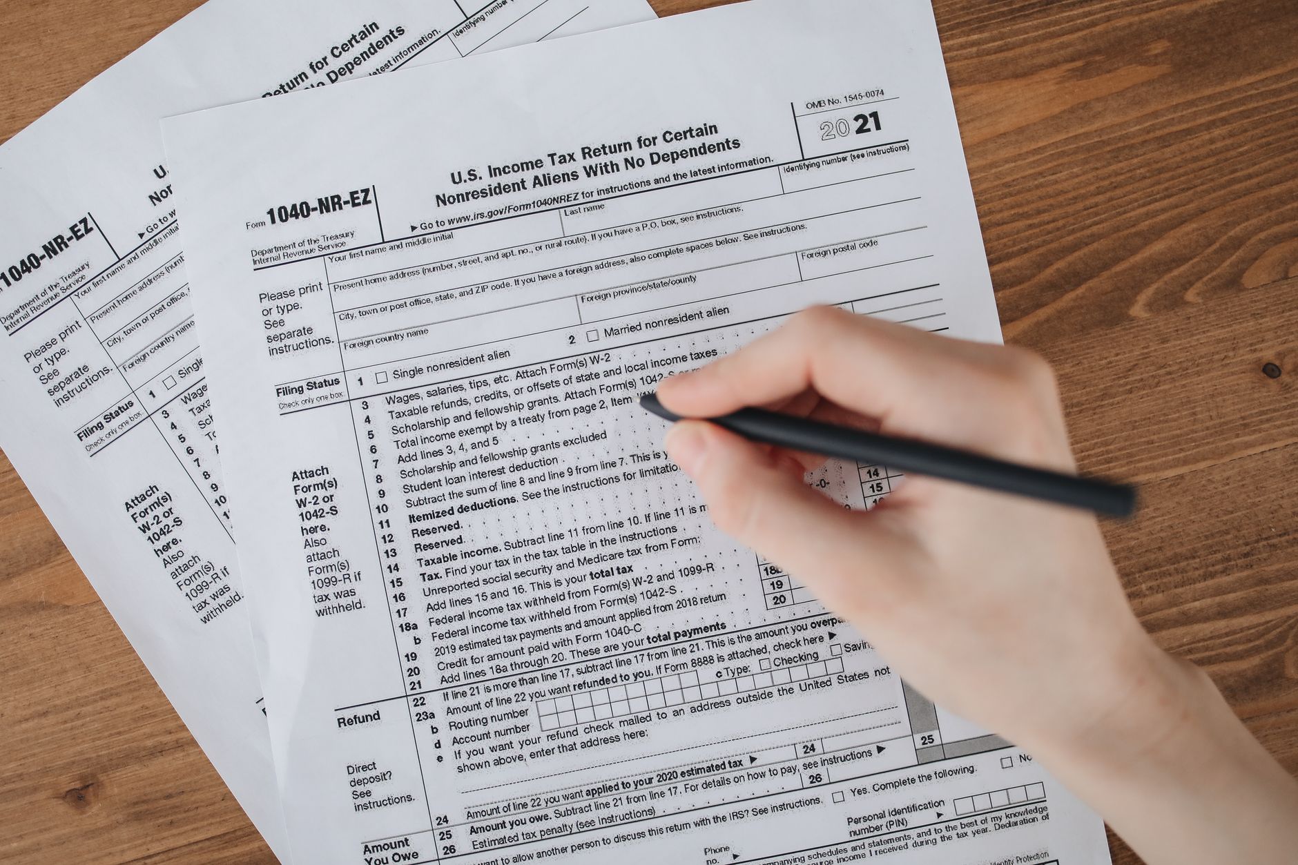 A hand filling out a U.S. income tax return form with a pen