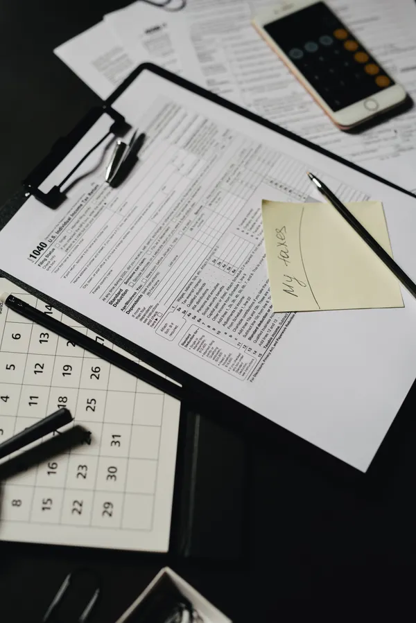 A tax form with a calendar, a pen, and a phone calculator app