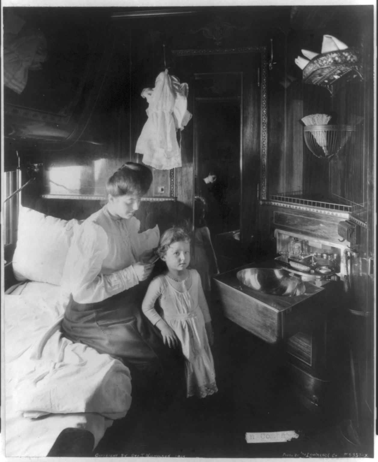 A mother and child in a train compartment in an early 20th-century photograph