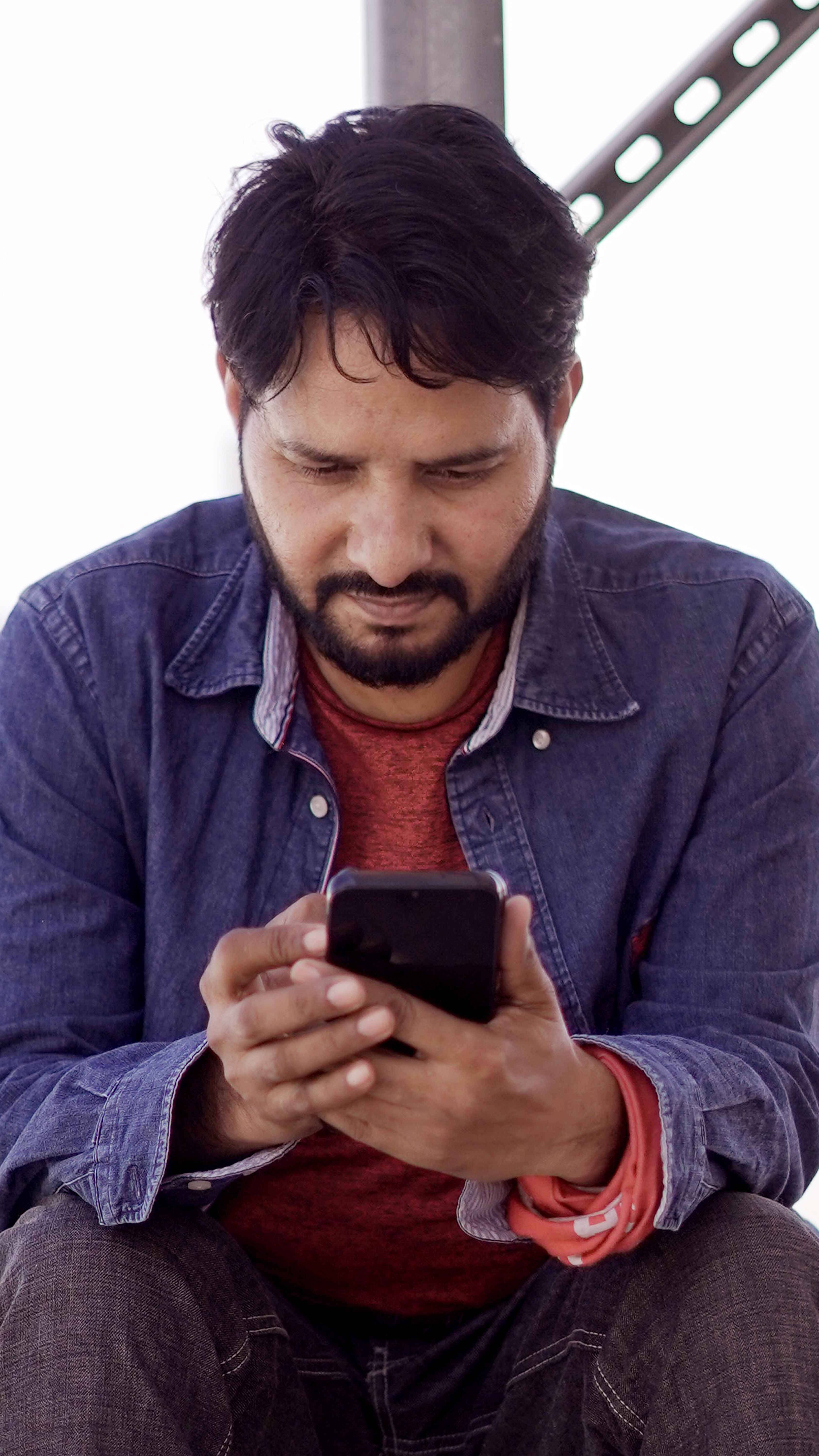 A man using a smartphone outdoors, tapping its touchscreen