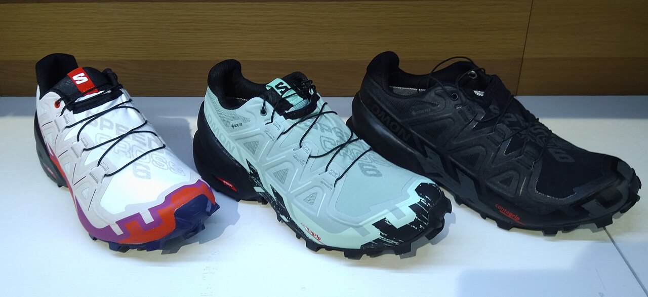 A pair of trail running shoes with deep lugged outsoles designed for muddy terrain