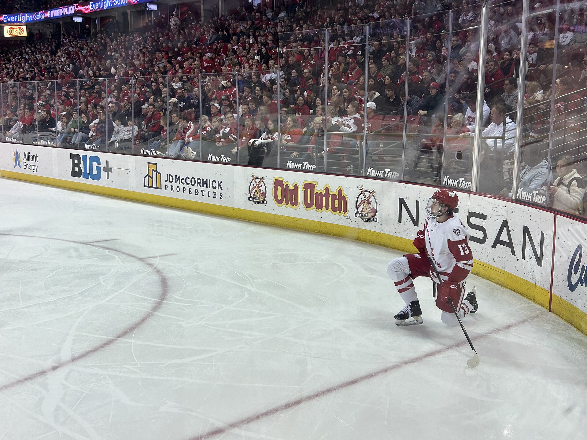 A college hockey player skates with the puck during a game