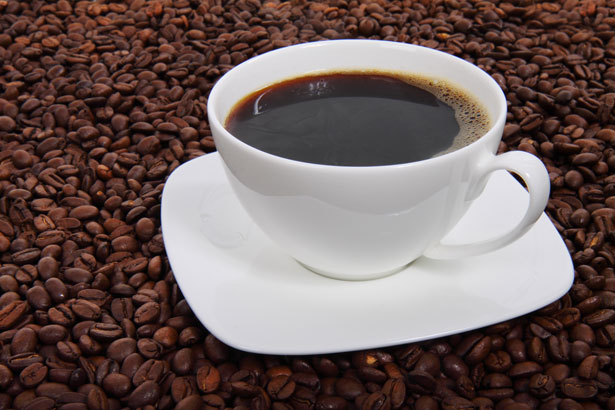 A cup of coffee surrounded by coffee beans