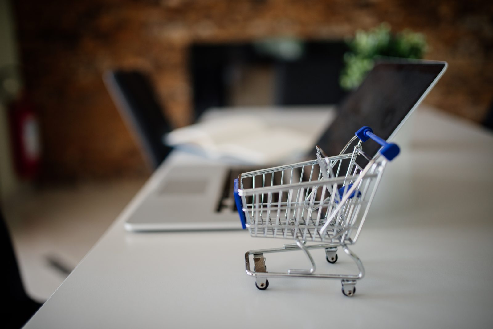 A miniature shopping cart beside a laptop